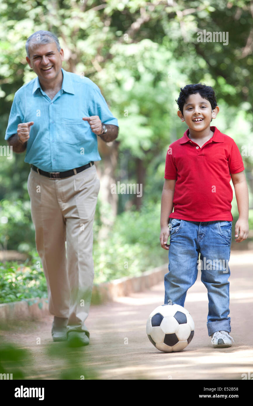 Grandson playing soccer as grandfather watches on Stock Photo