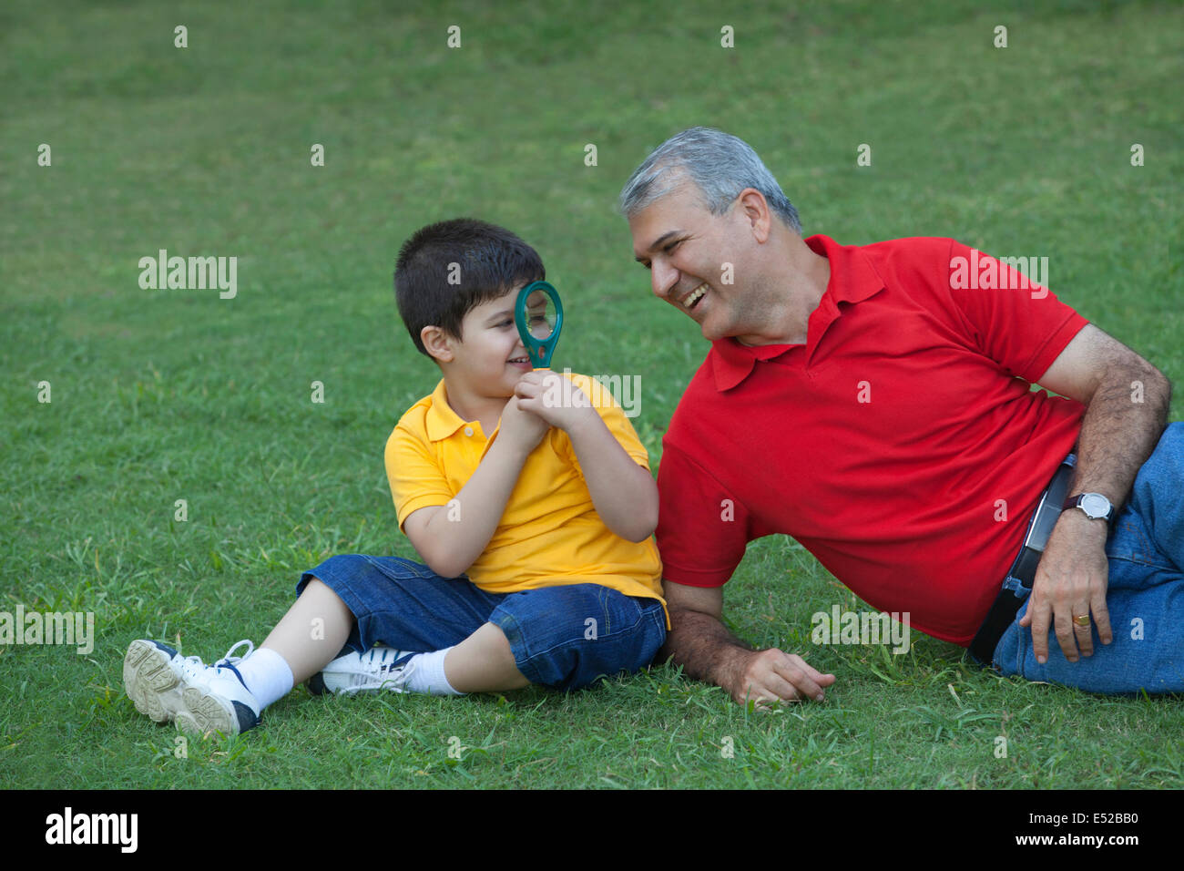 Young boy looking at grandfather through magnifying glass Stock Photo