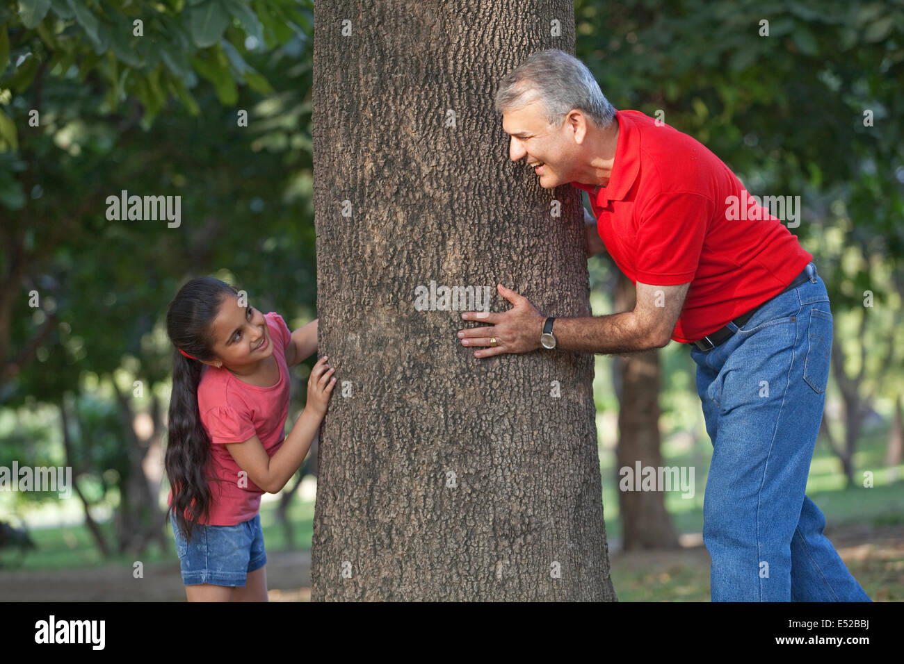 Grandfather and granddaughter playing hide and seek in a park Stock Photo