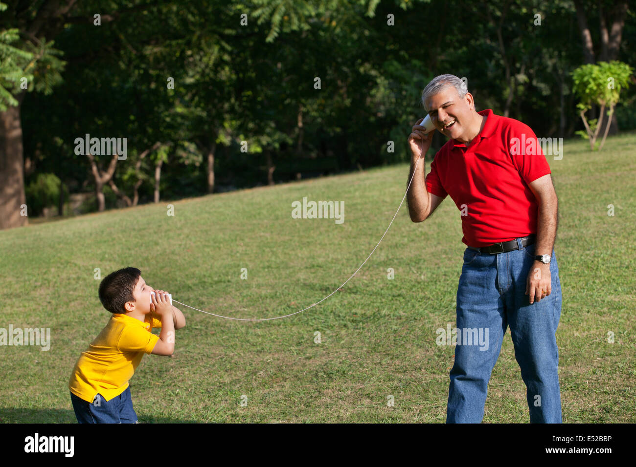 Grandfather and grandson talking through paper cups Stock Photo