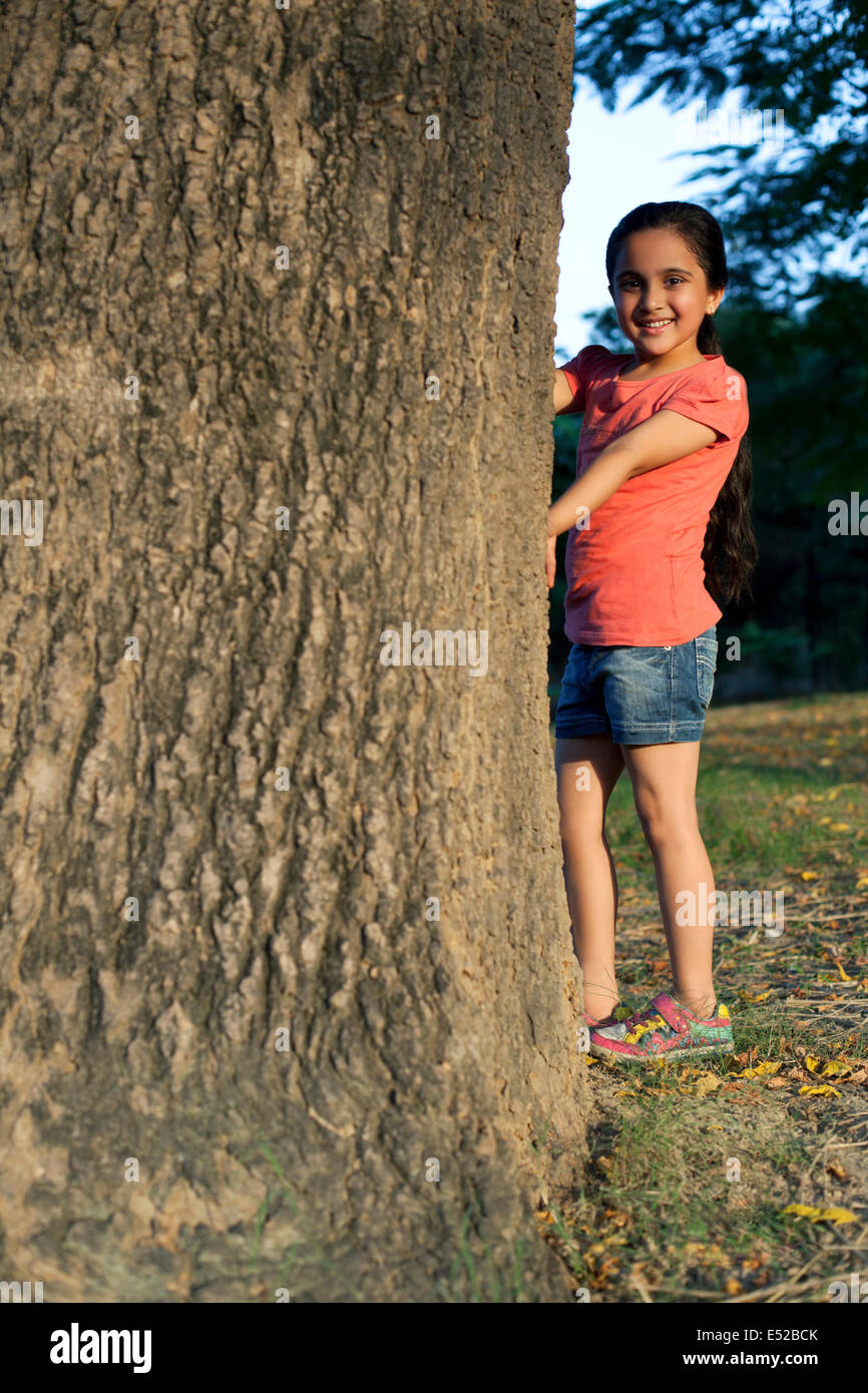 Portrait of a young girl standing beside a tree Stock Photo