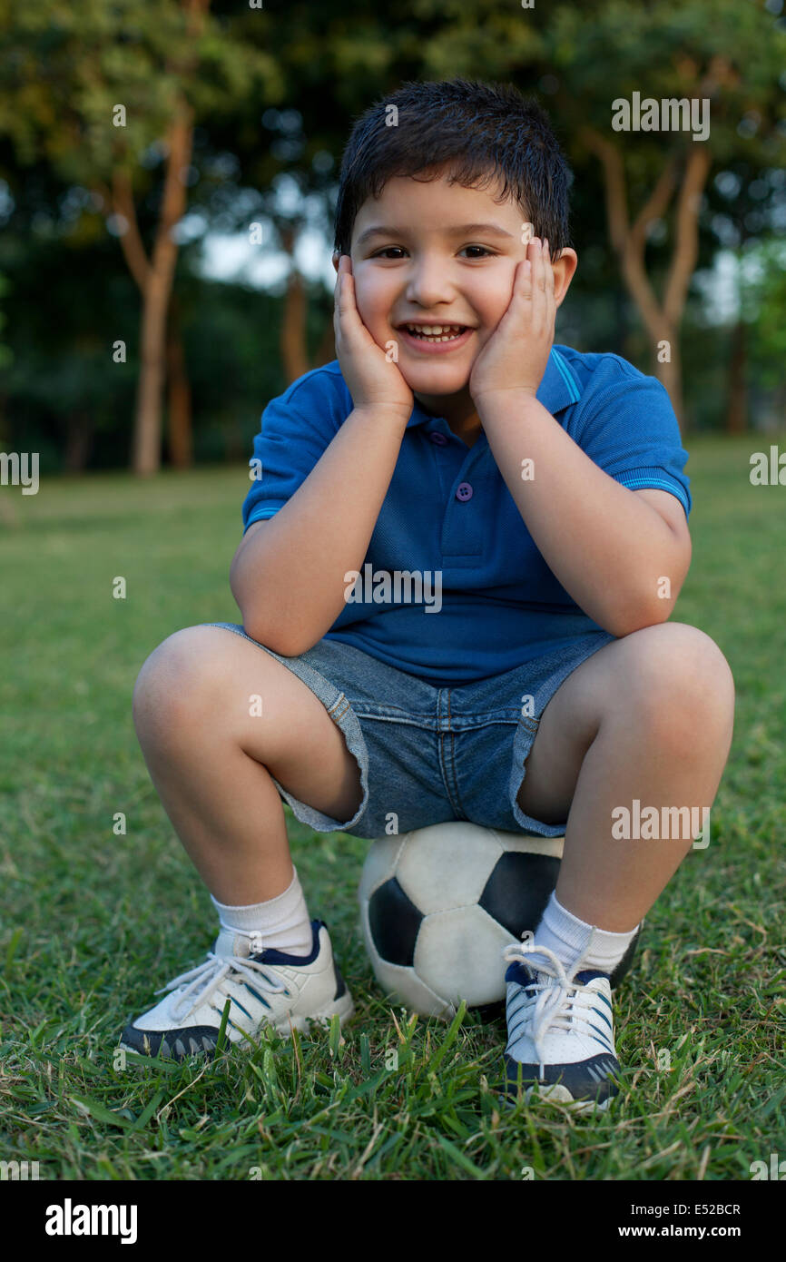 Portrait of a young boy sitting on a football Stock Photo
