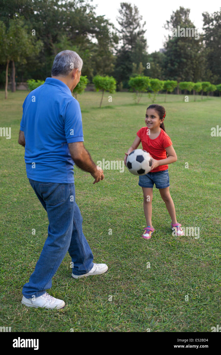 Grandfather and granddaughter playing with a football Stock Photo