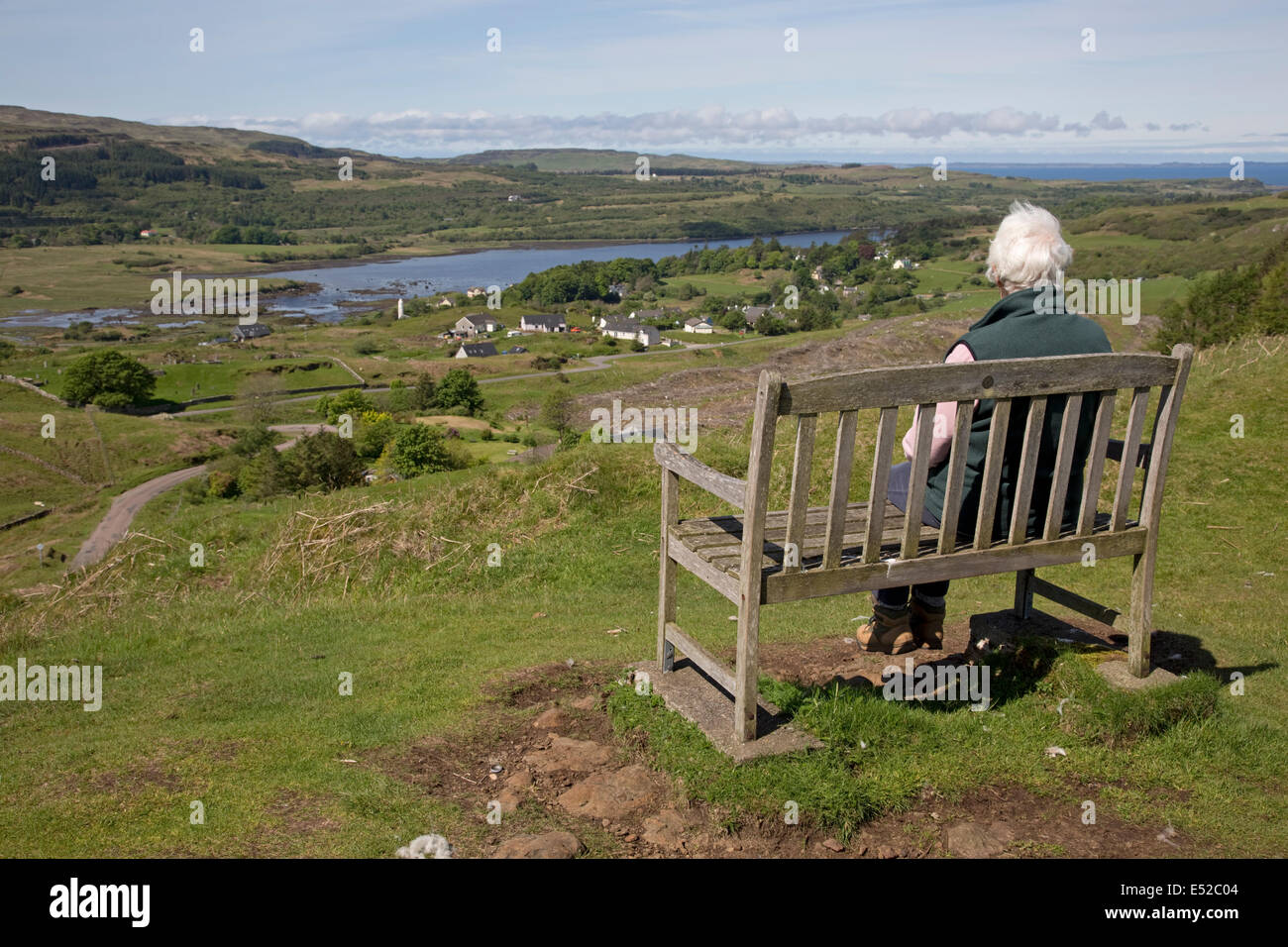 Woman sitting on bench admiring view Dervaig Isle of Mull Scotland Stock Photo