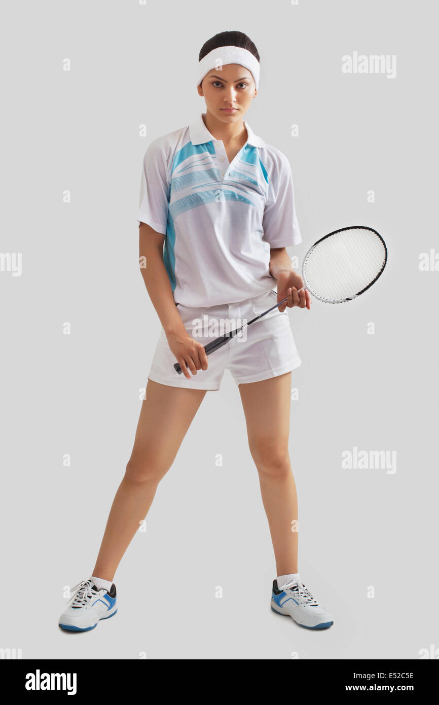 Full length portrait of young woman holding badminton racket isolated