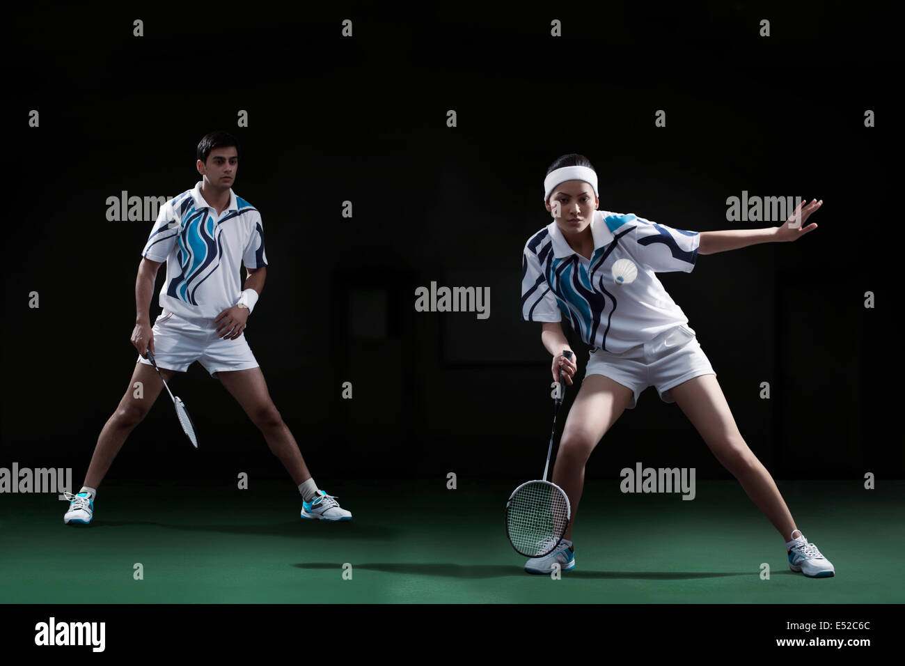 Woman hitting shuttlecock with badminton racket with partner looking at her Stock Photo