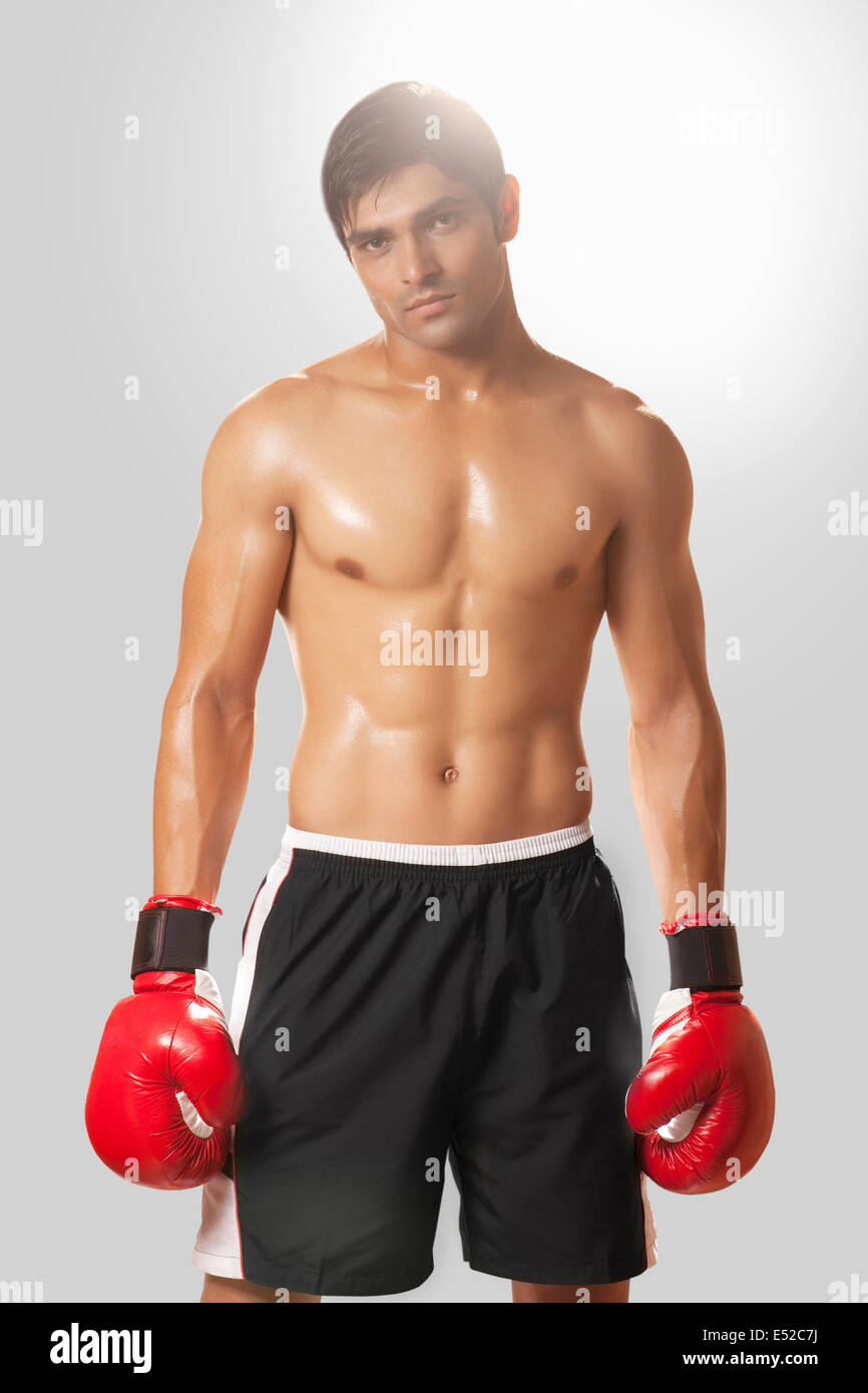 Portrait of shirtless young man wearing boxing gloves against white  background Stock Photo - Alamy