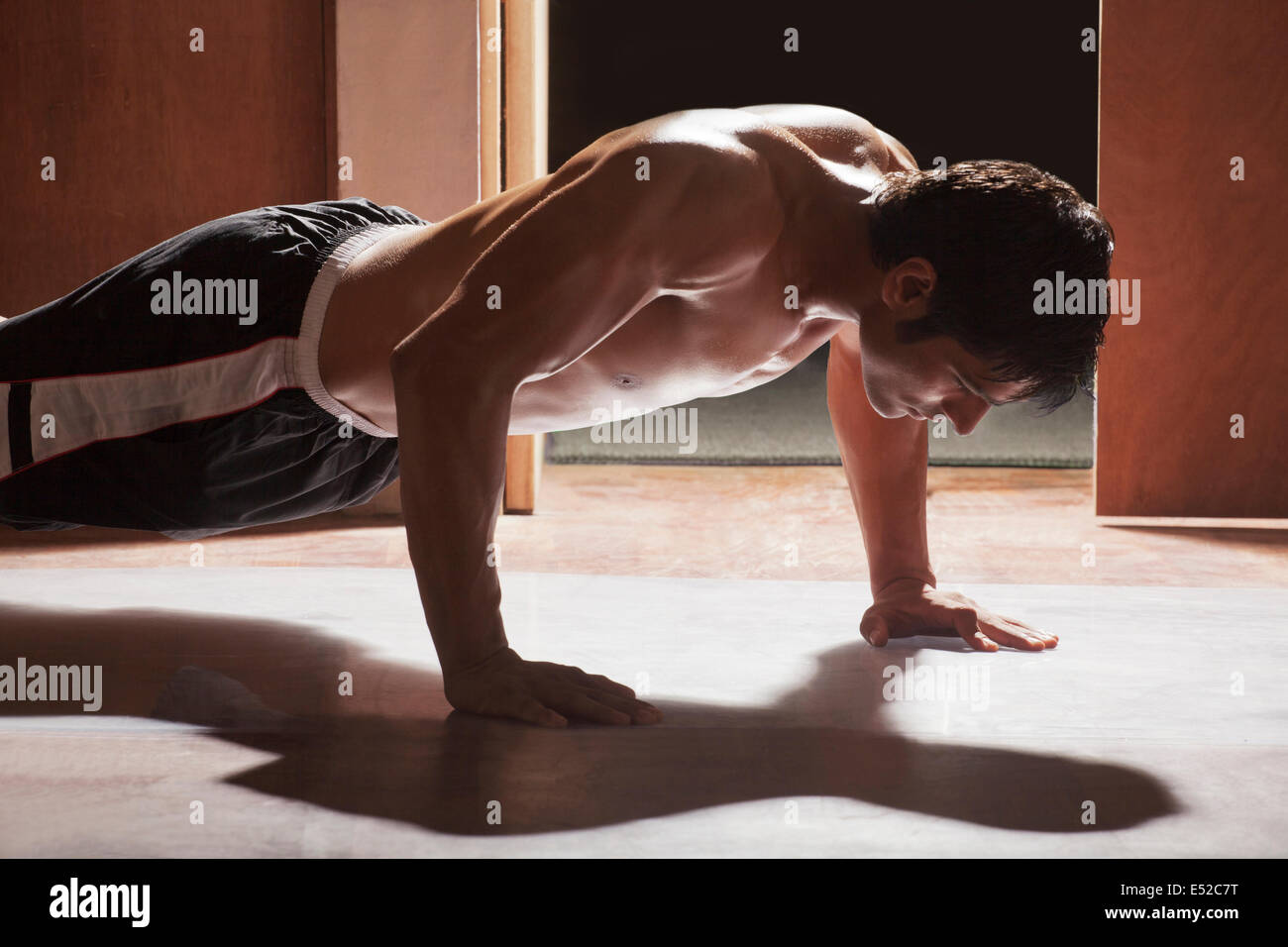 Side view of young man doing push-ups in gym Stock Photo