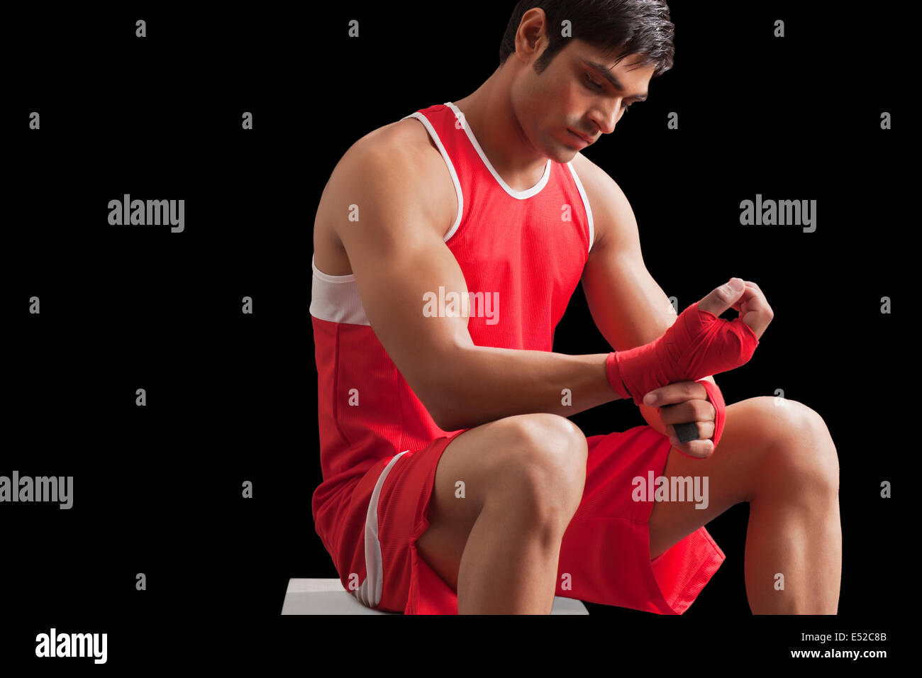 An Indian male boxer taping up hands against black background Stock Photo
