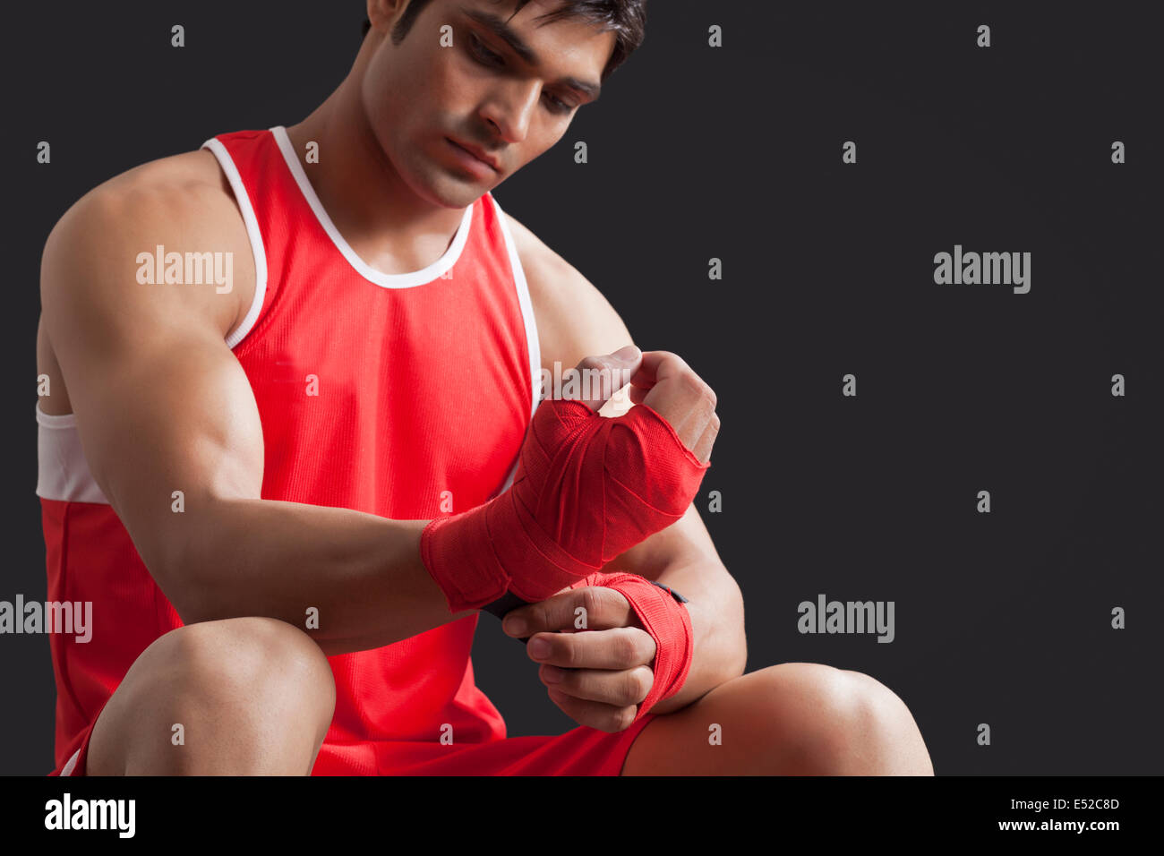 Confident male boxer taping up hands over black background Stock Photo