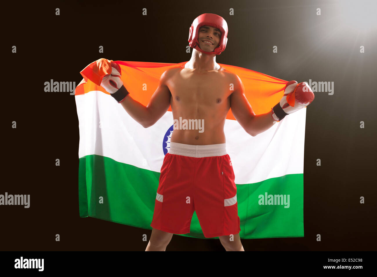 Happy Indian male boxer with national flag standing against black background Stock Photo