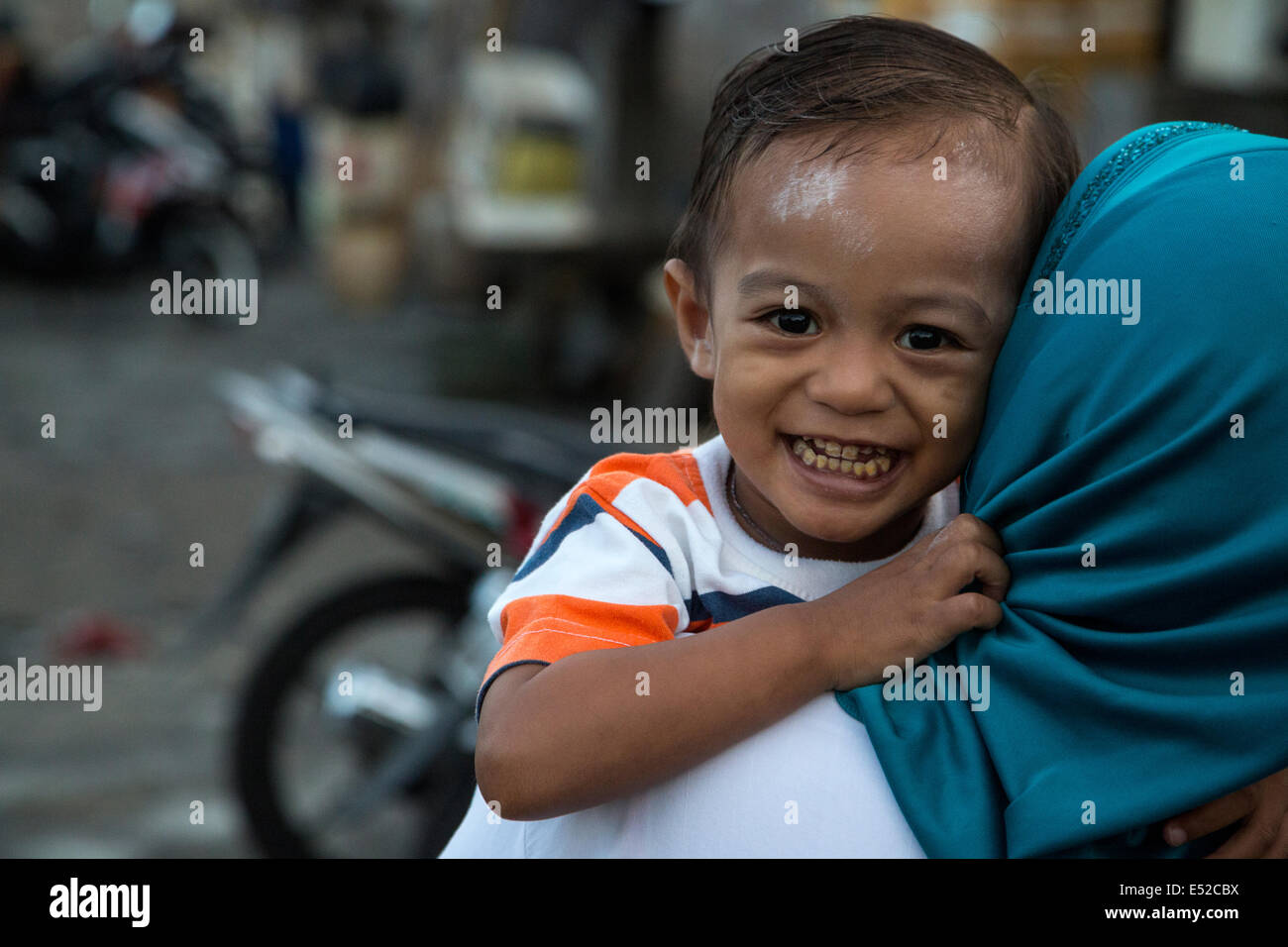 Bali, Indonesia.  Little Boy Being Carried by his Mother. Stock Photo