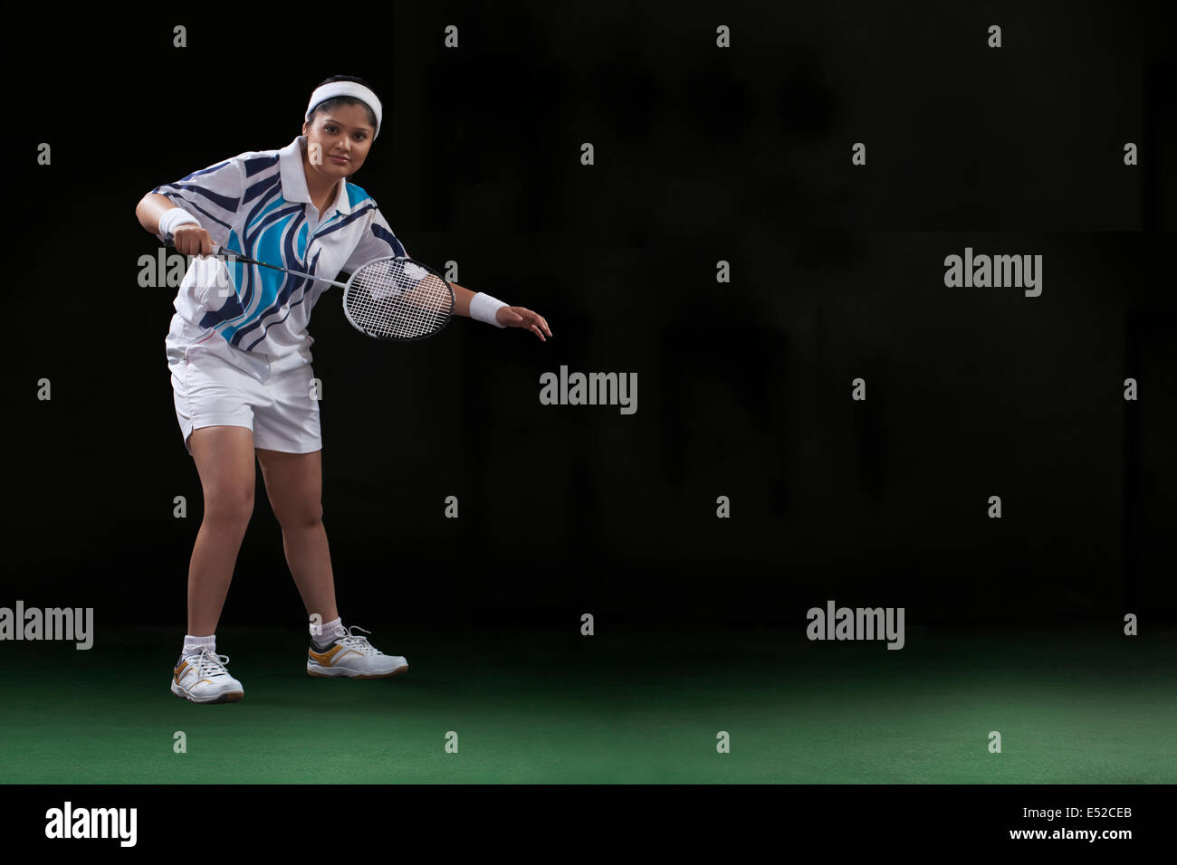 Full length portrait of young woman playing badminton isolated over black background Stock Photo