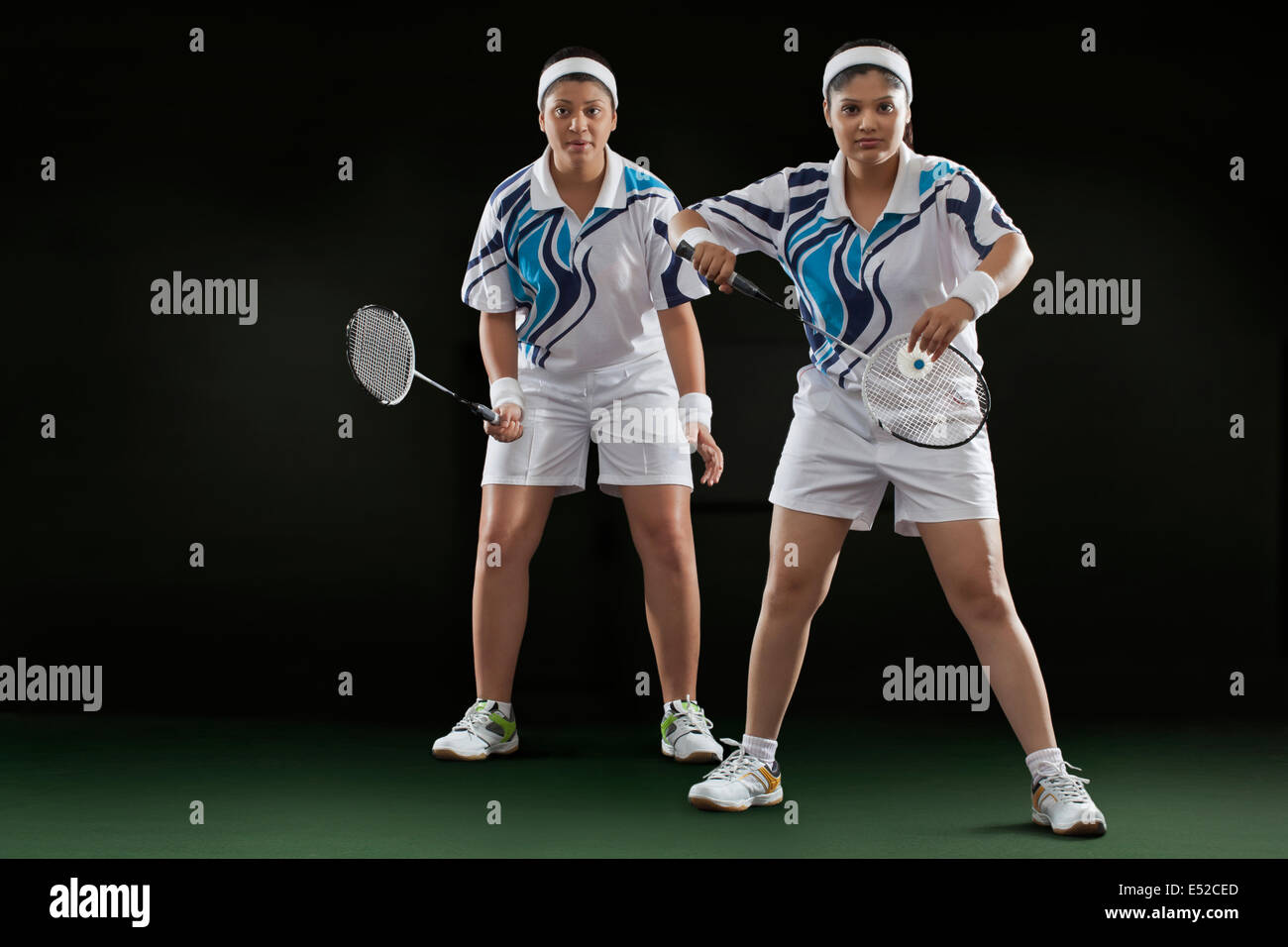 Female partners playing badminton over black background Stock Photo
