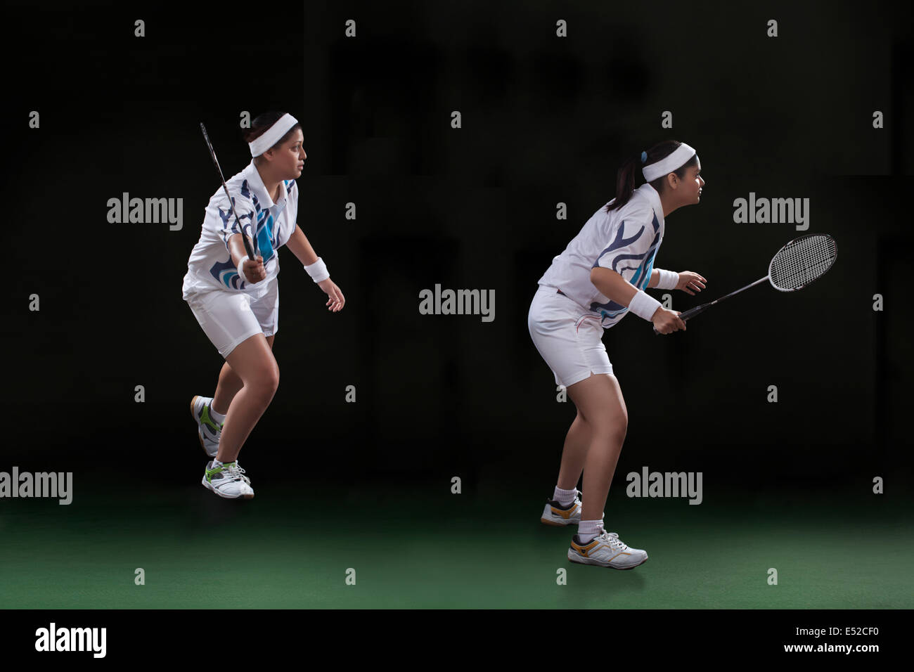 Profile shot of female players playing doubles badminton over black background Stock Photo
