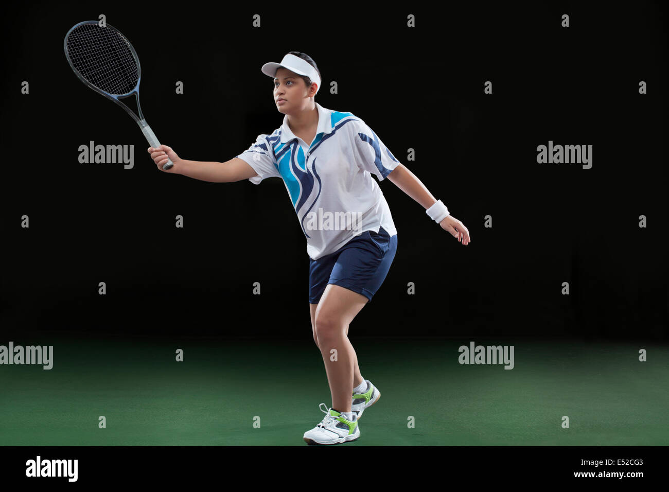 Young female player in sportswear playing tennis over black background Stock Photo