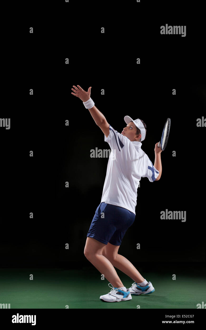 Young woman in sportswear playing tennis isolated over black background Stock Photo