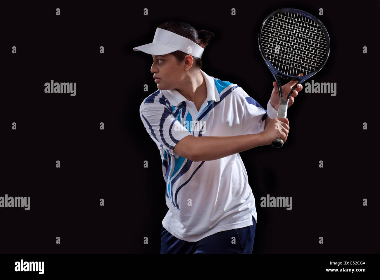 Young Indian woman playing tennis over black background Stock Photo