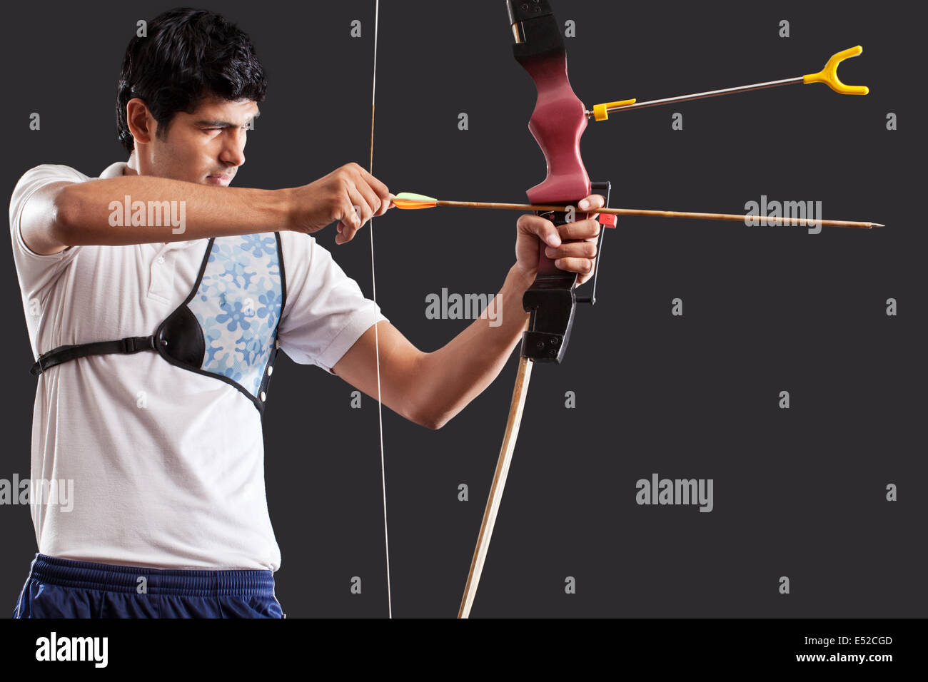 Man aiming bow and arrow isolated over black background Stock Photo