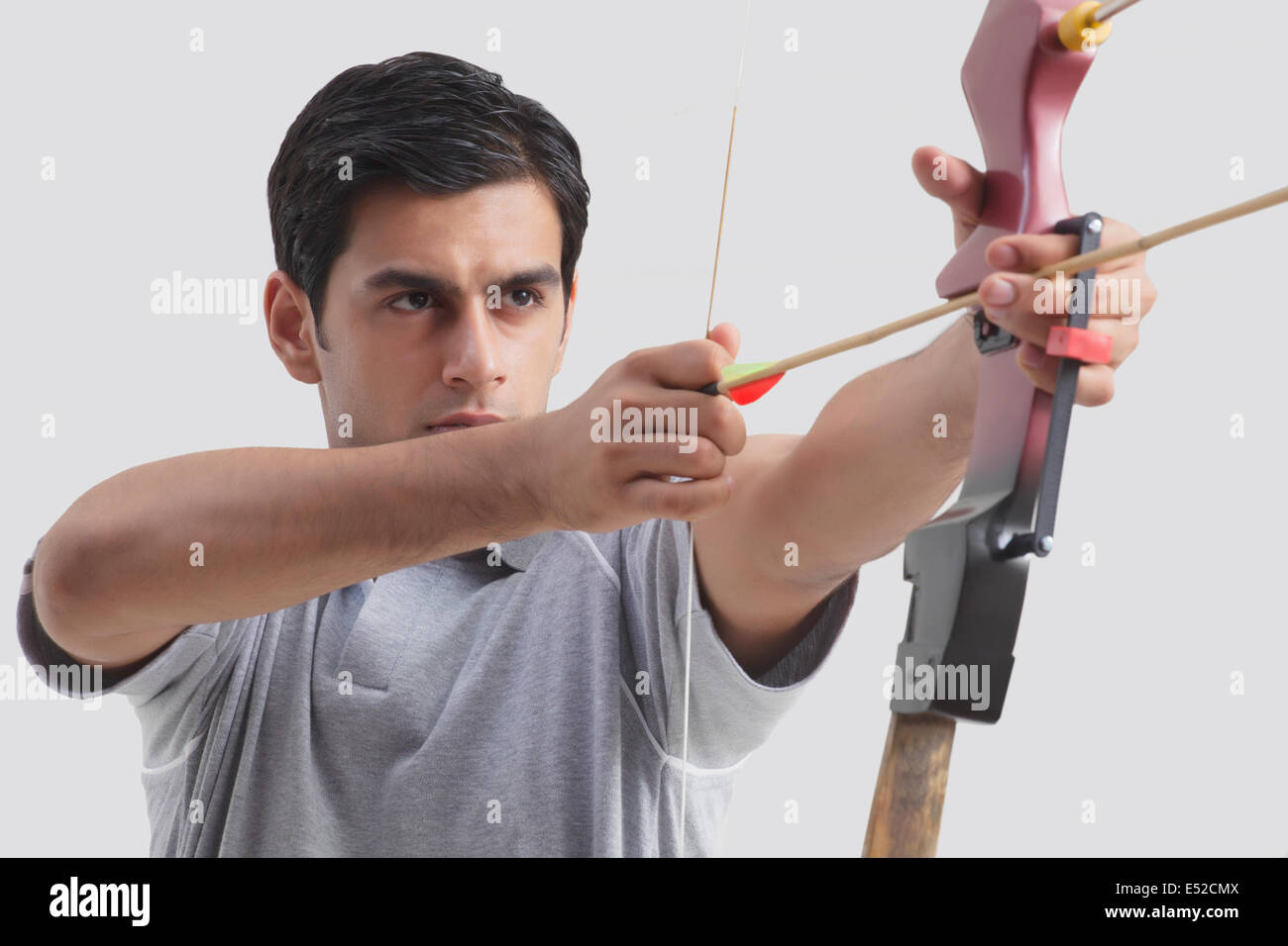Male archer taking aim with competition bow against gray background Stock Photo