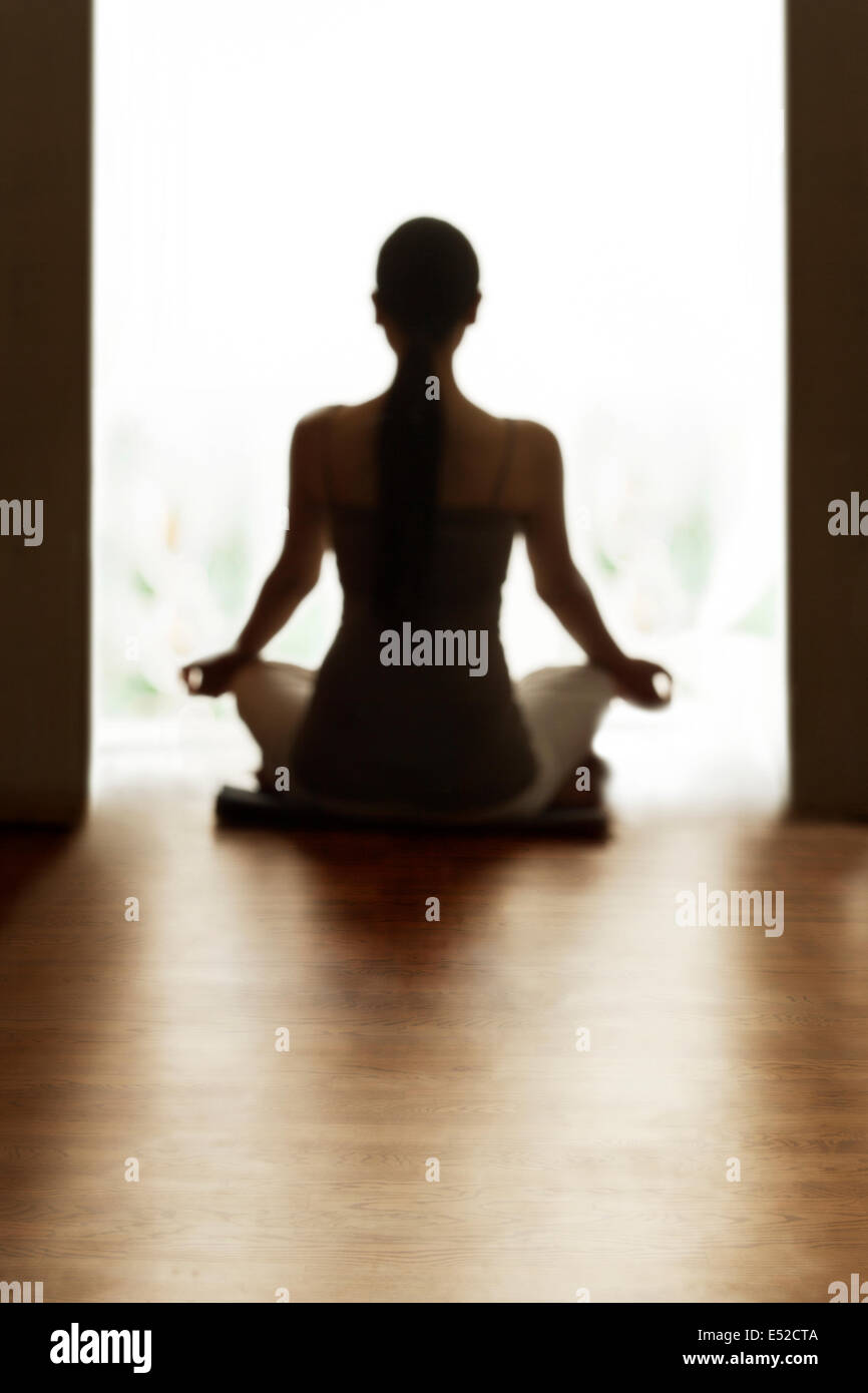 Rear view of woman meditating on floor Stock Photo - Alamy