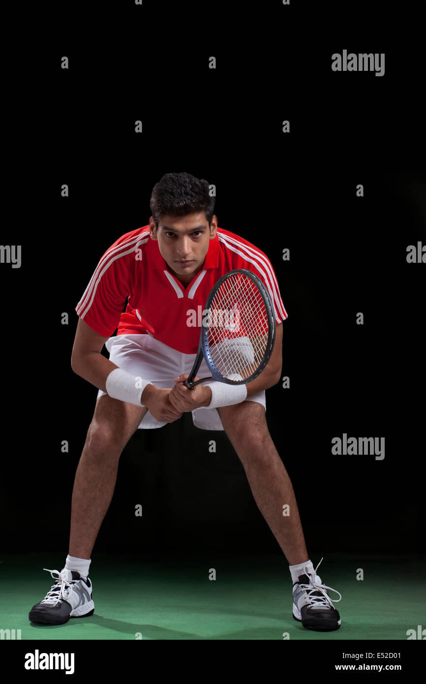 Full length portrait of young male player playing tennis over black background Stock Photo