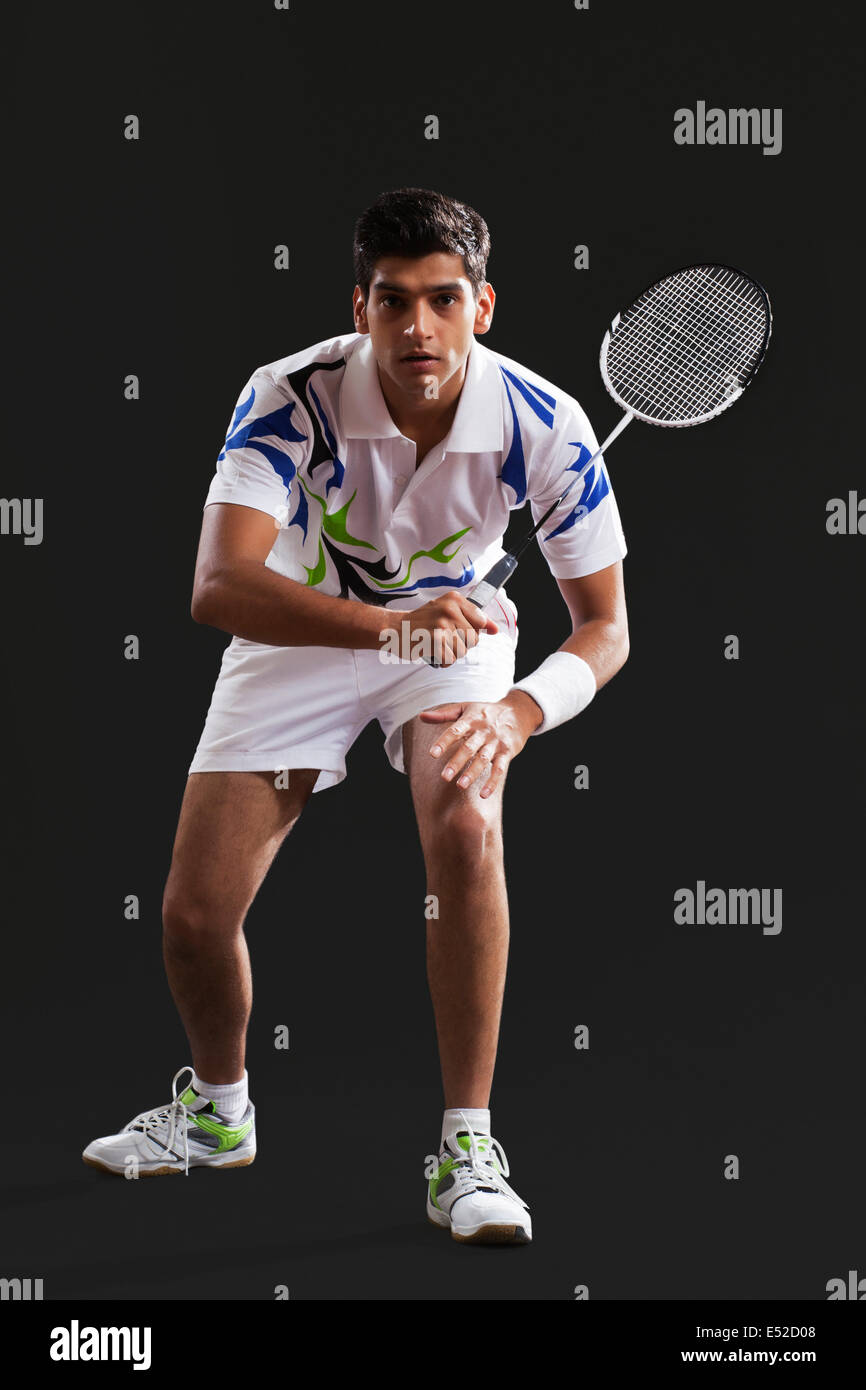 Full length portrait of young man playing badminton over black background Stock Photo