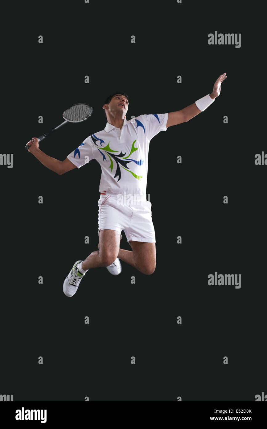 Young male player holding badminton racket while jumping in midair