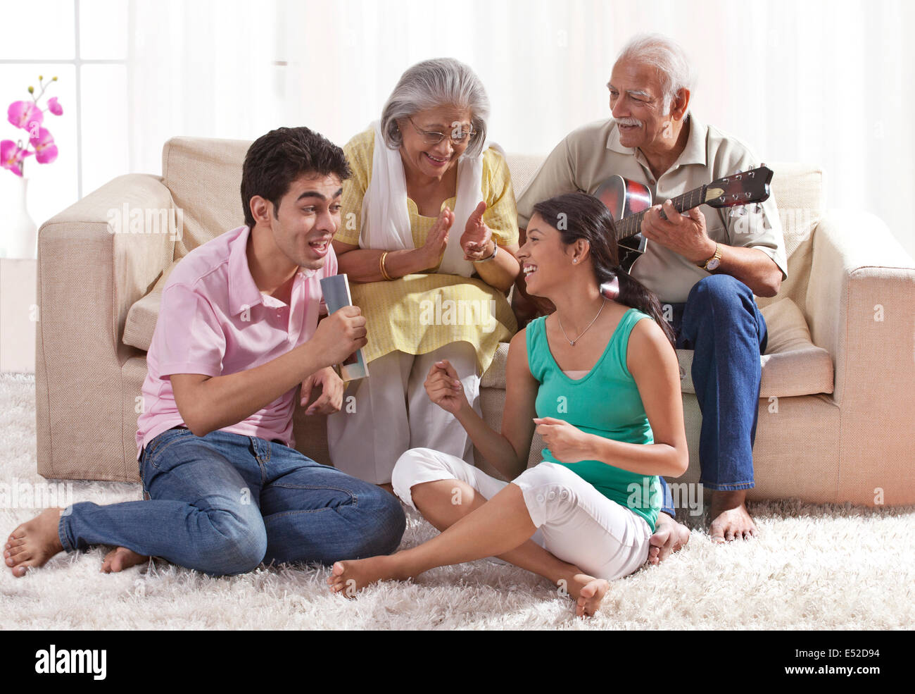 Grandfather playing the guitar with grandmother and grandchildren singing Stock Photo