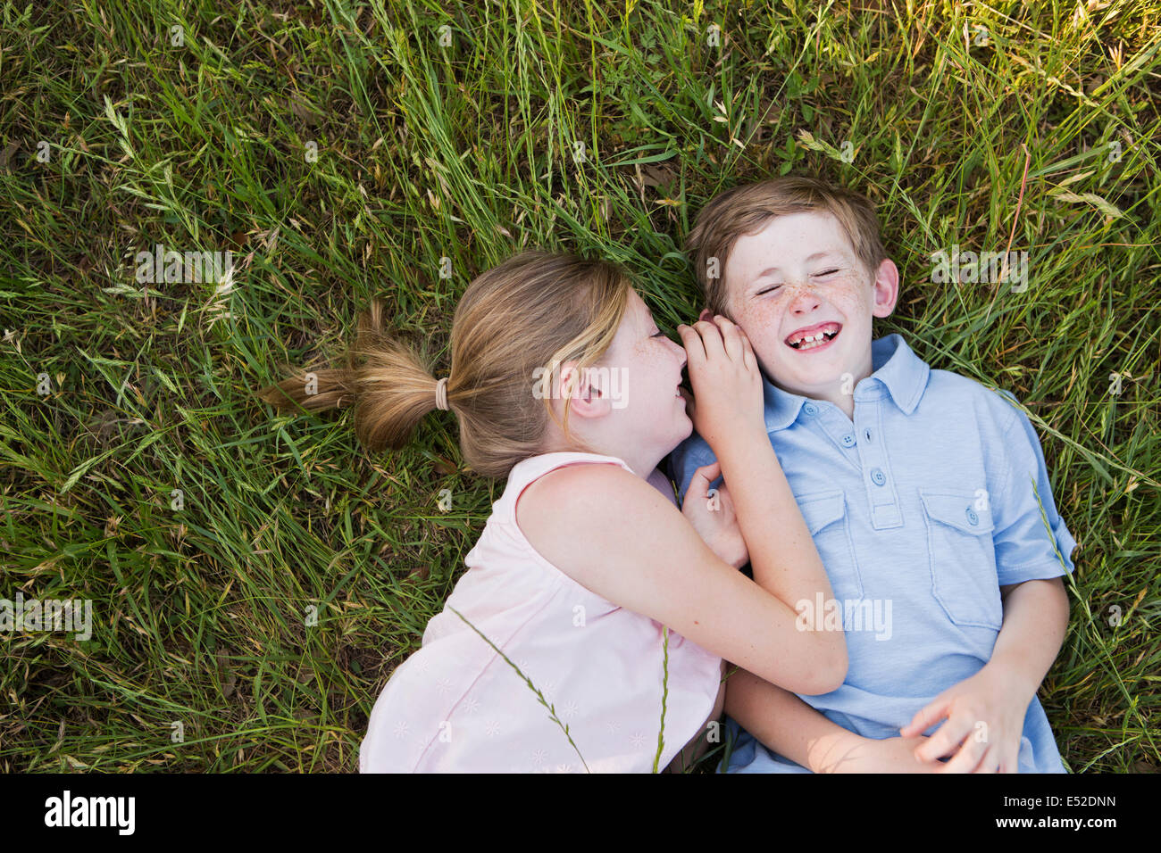 Two children, brother and sister lying side by side on the grass Stock Photo