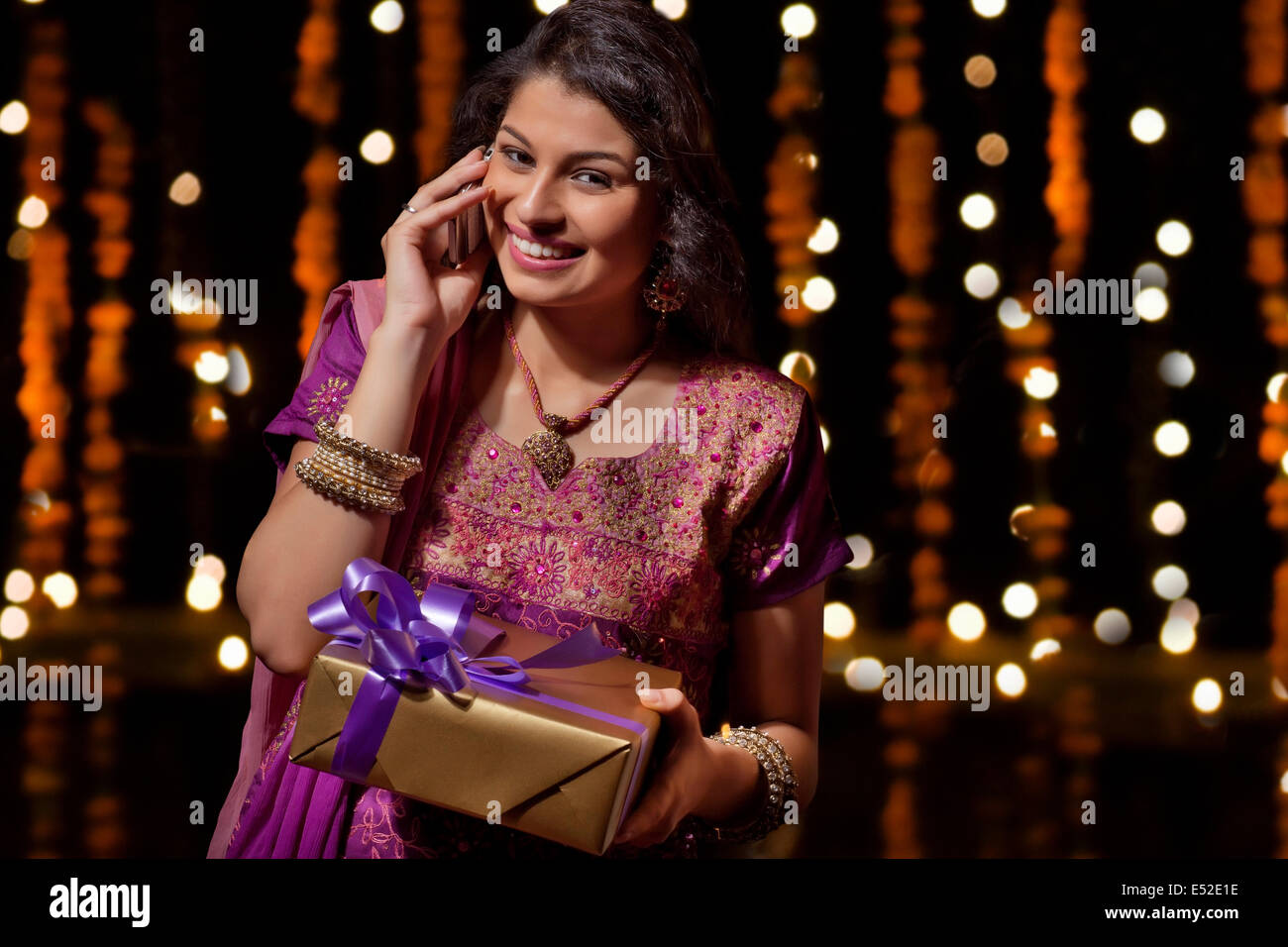 Portrait of woman with gift talking on mobile phone Stock Photo