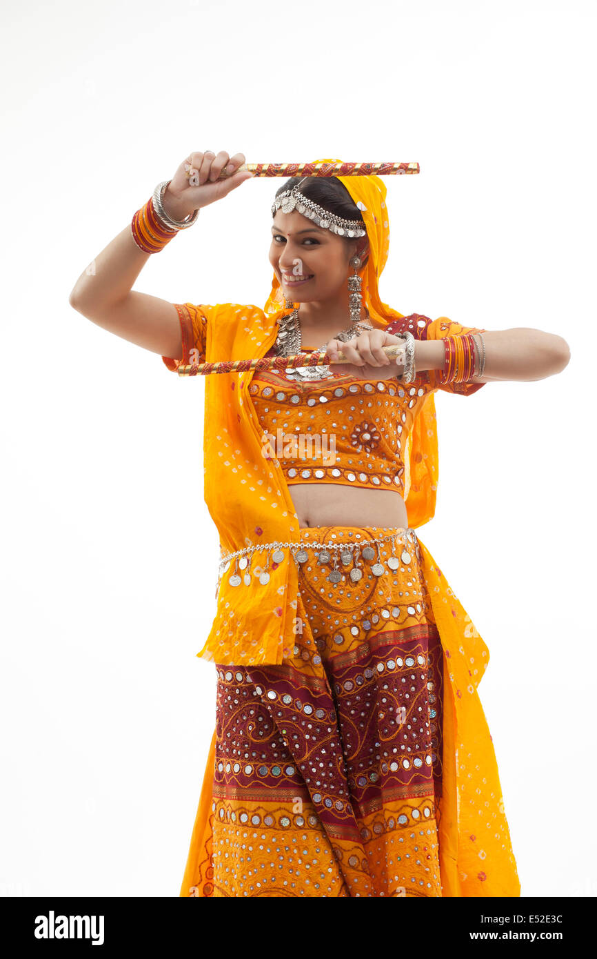 Portrait of beautiful young woman performing Dandiya Raas against white background Stock Photo