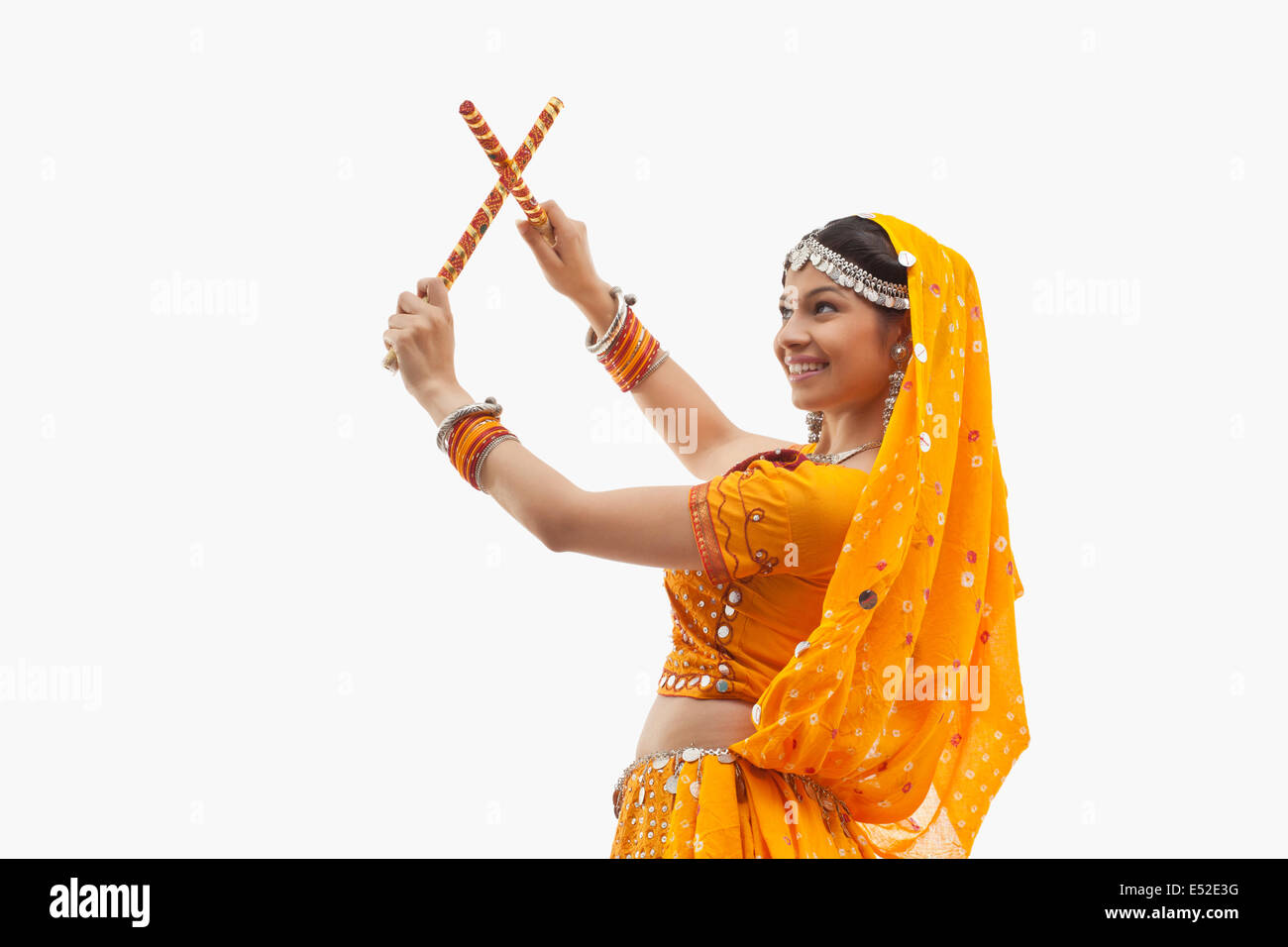 Young woman in traditional wear performing Dandiya Raas over white ...