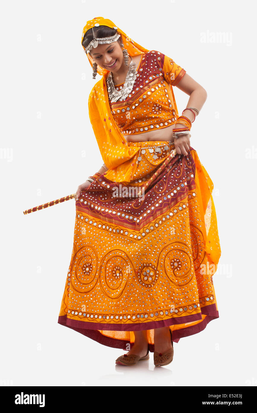 Full length of happy woman in chaniya choli performing Dandiya Raas ...
