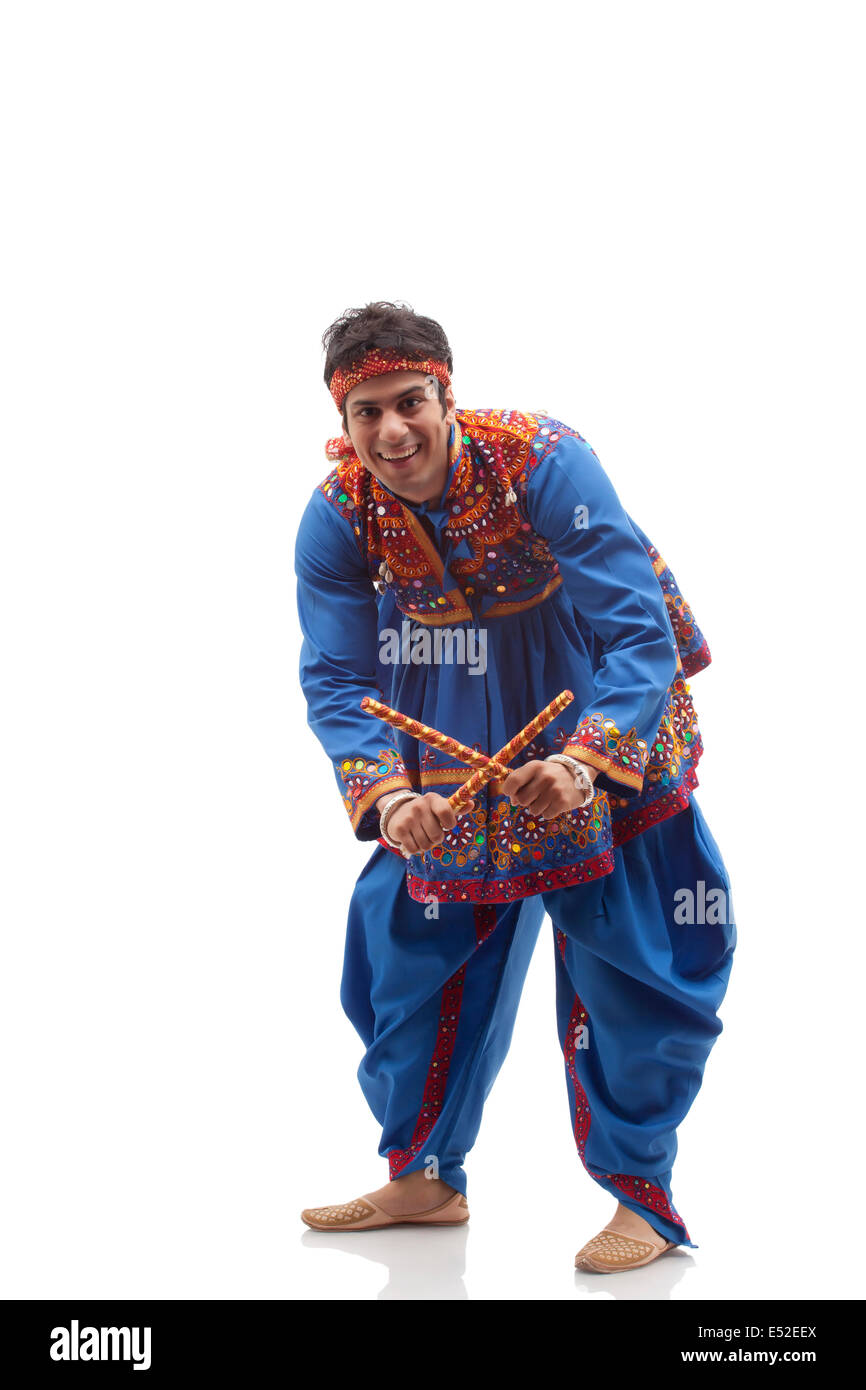 Portrait of happy young man in kedia and dhoti performing Dandiya Rass ...