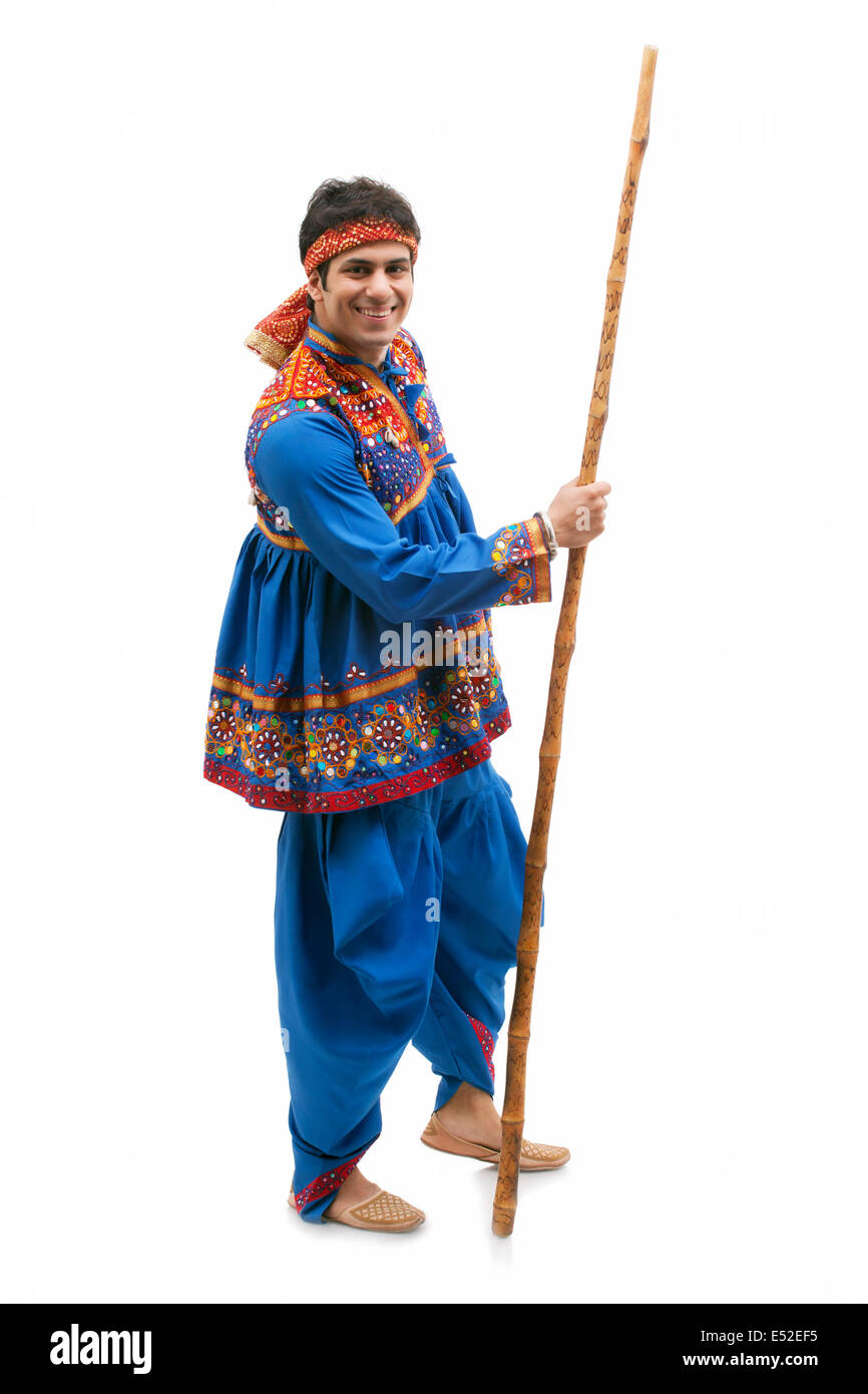 Full length portrait of happy young man in traditional wear holding stick isolated over white background Stock Photo