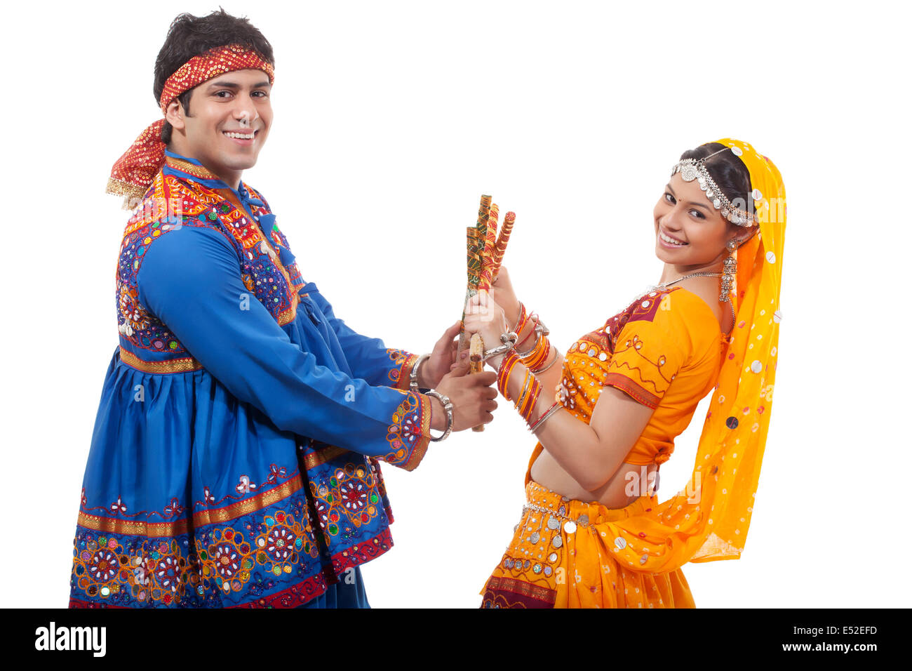 Portrait of happy young couple performing Dandiya Raas over white background Stock Photo