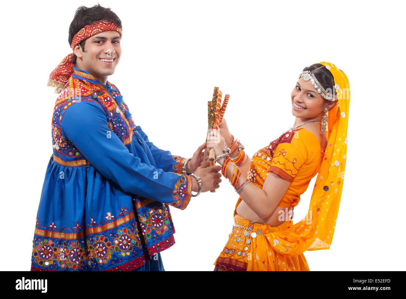 Portrait of happy young couple performing Dandiya Raas over white ...