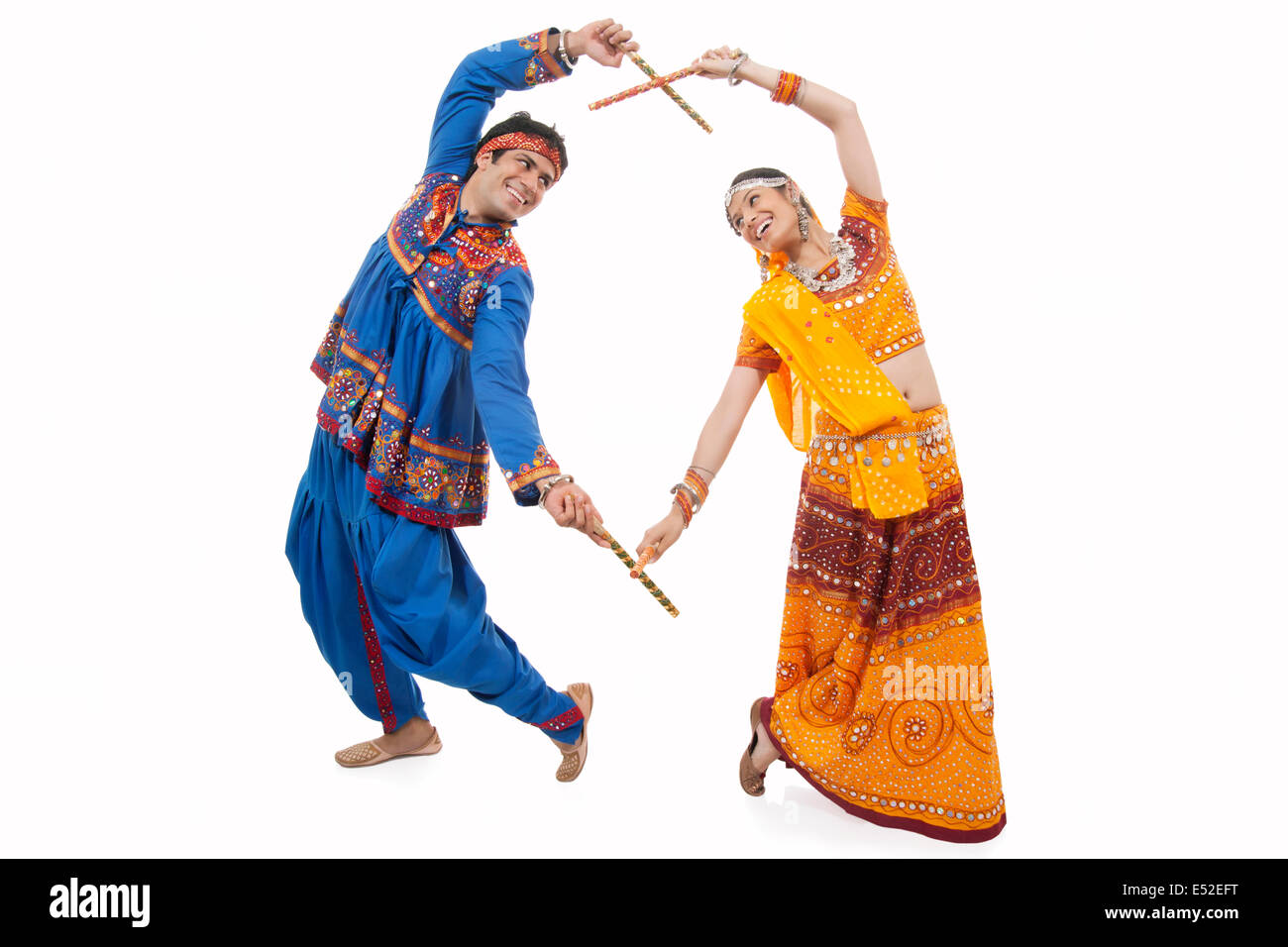 An Indian couple in traditional wear performing Dandiya Raas over white background Stock Photo