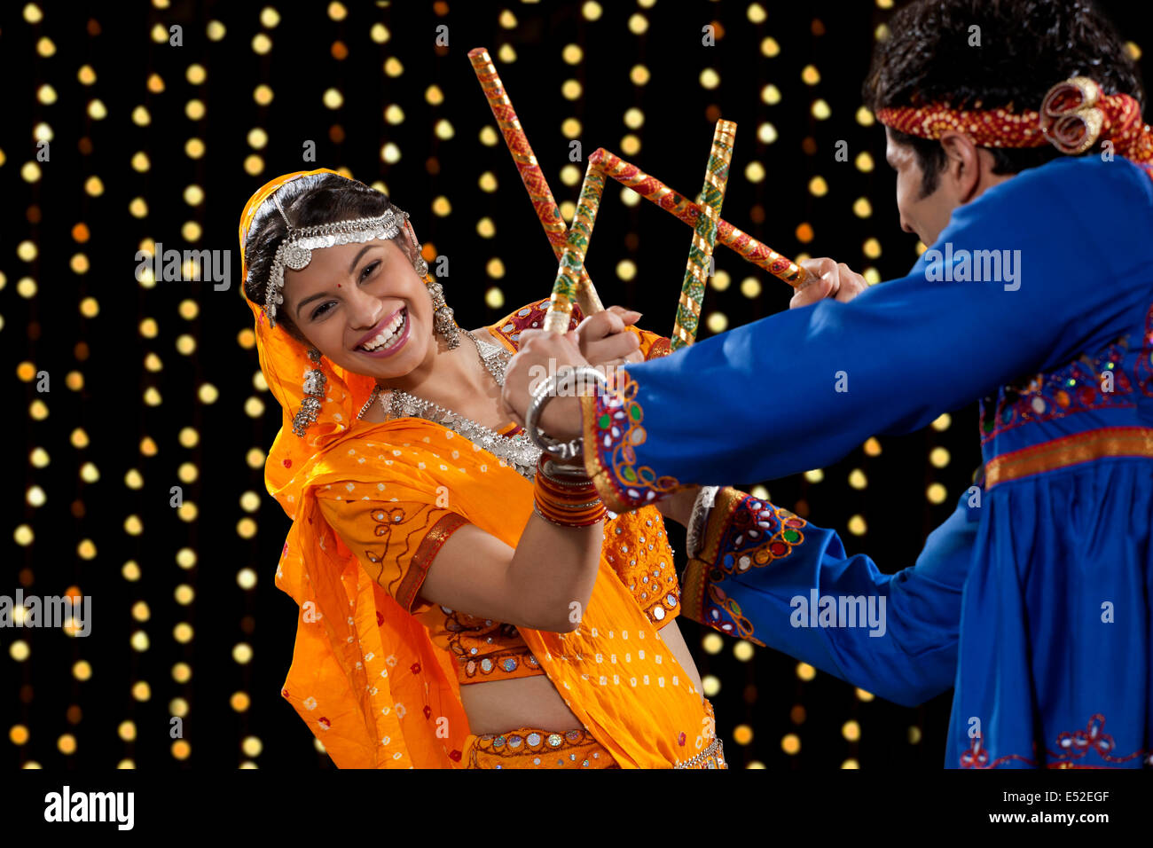 Portrait of happy young woman performing Dandiya Raas with man against ...