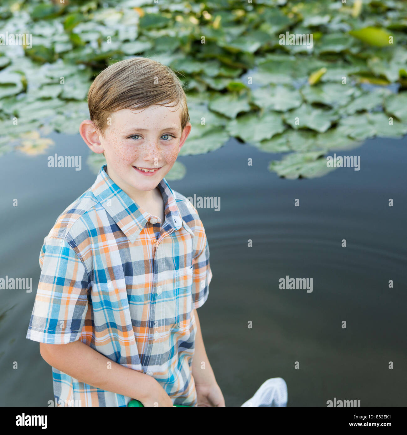 A young boy standing in shallow water with a fishing net. Stock Photo