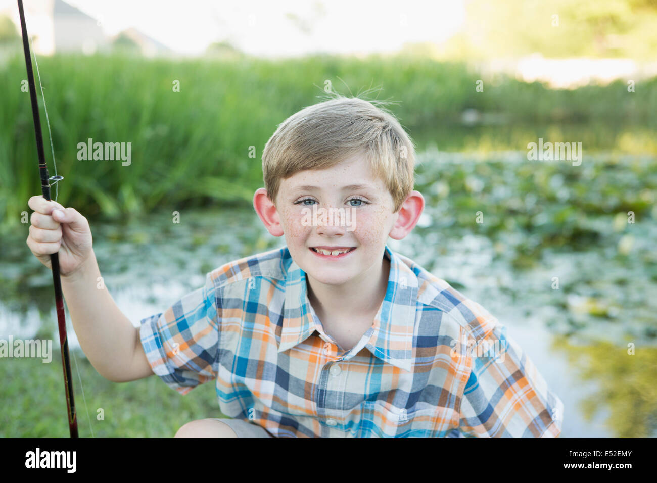 A young boy with his fishing road, by a lake or river. Stock Photo