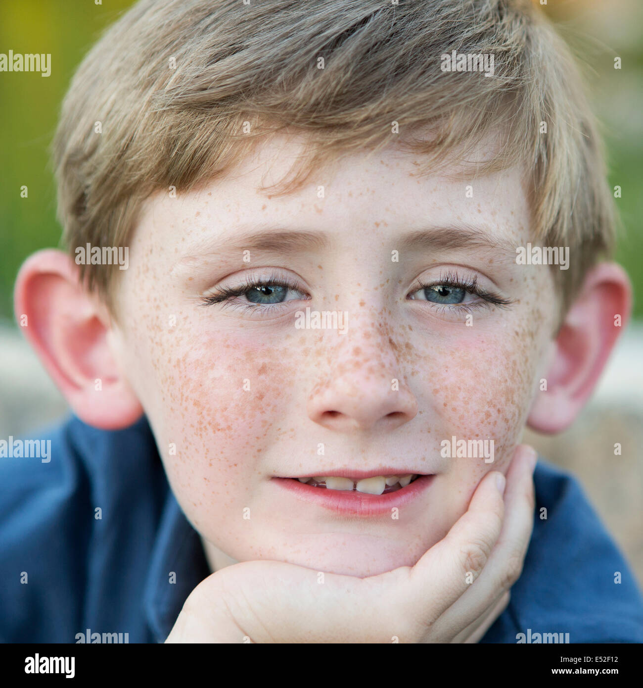 Head and shoulders portrait of a young boy sitting with his chin resting on his hand. Stock Photo