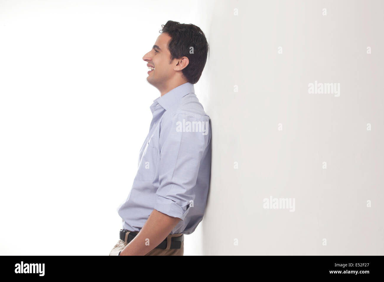 Man standing against a wall smiling Stock Photo Alamy