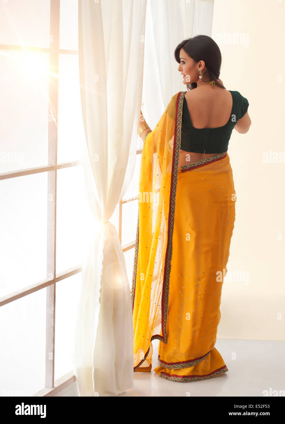 Woman in a saree looking out a window Stock Photo