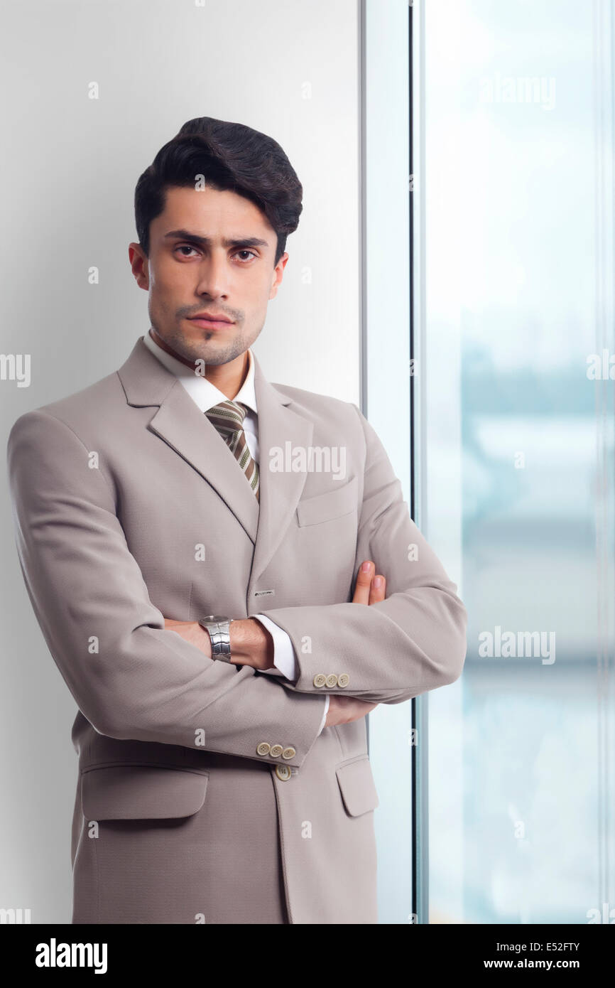 Portrait of young businessman standing arms crossed in office Stock ...