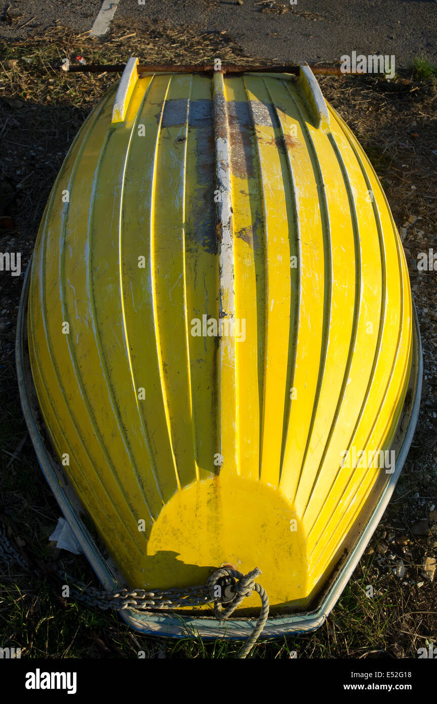 Yellow rowing boat tender upended Stock Photo