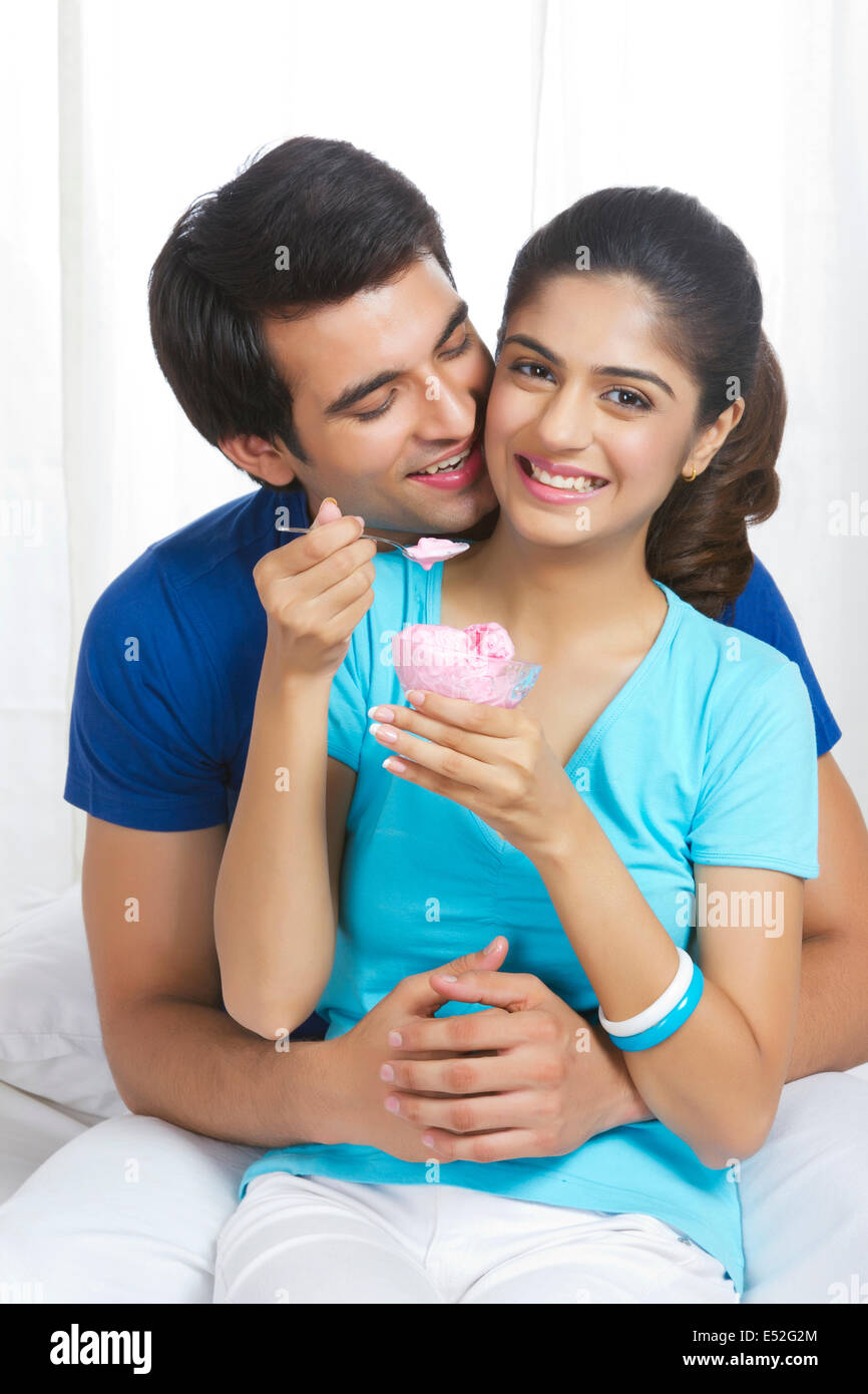 Romantic young man with woman eating ice-cream in bedroom Stock Photo ...