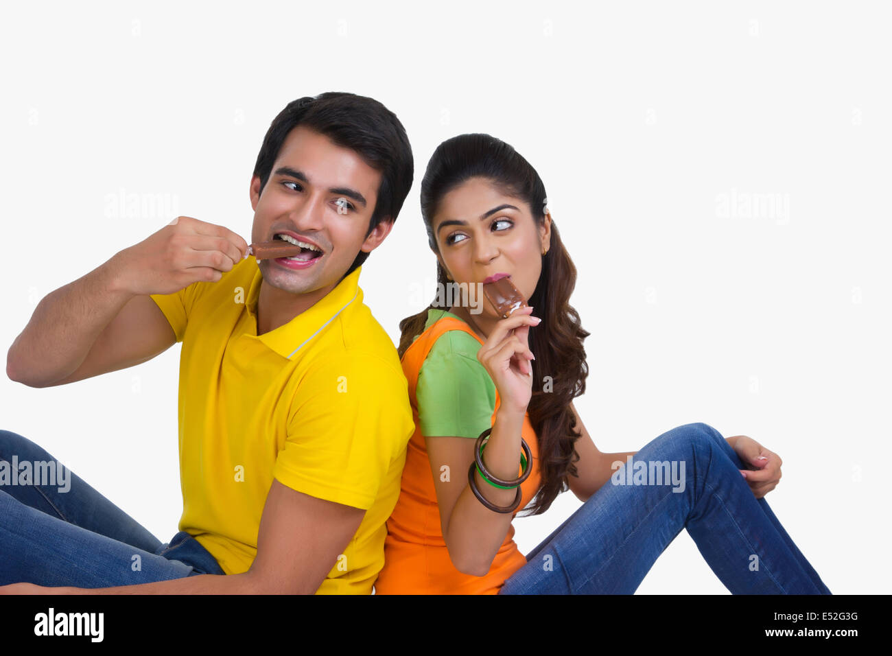 Young Indian couple enjoying ice-cream bars over white background Stock Photo