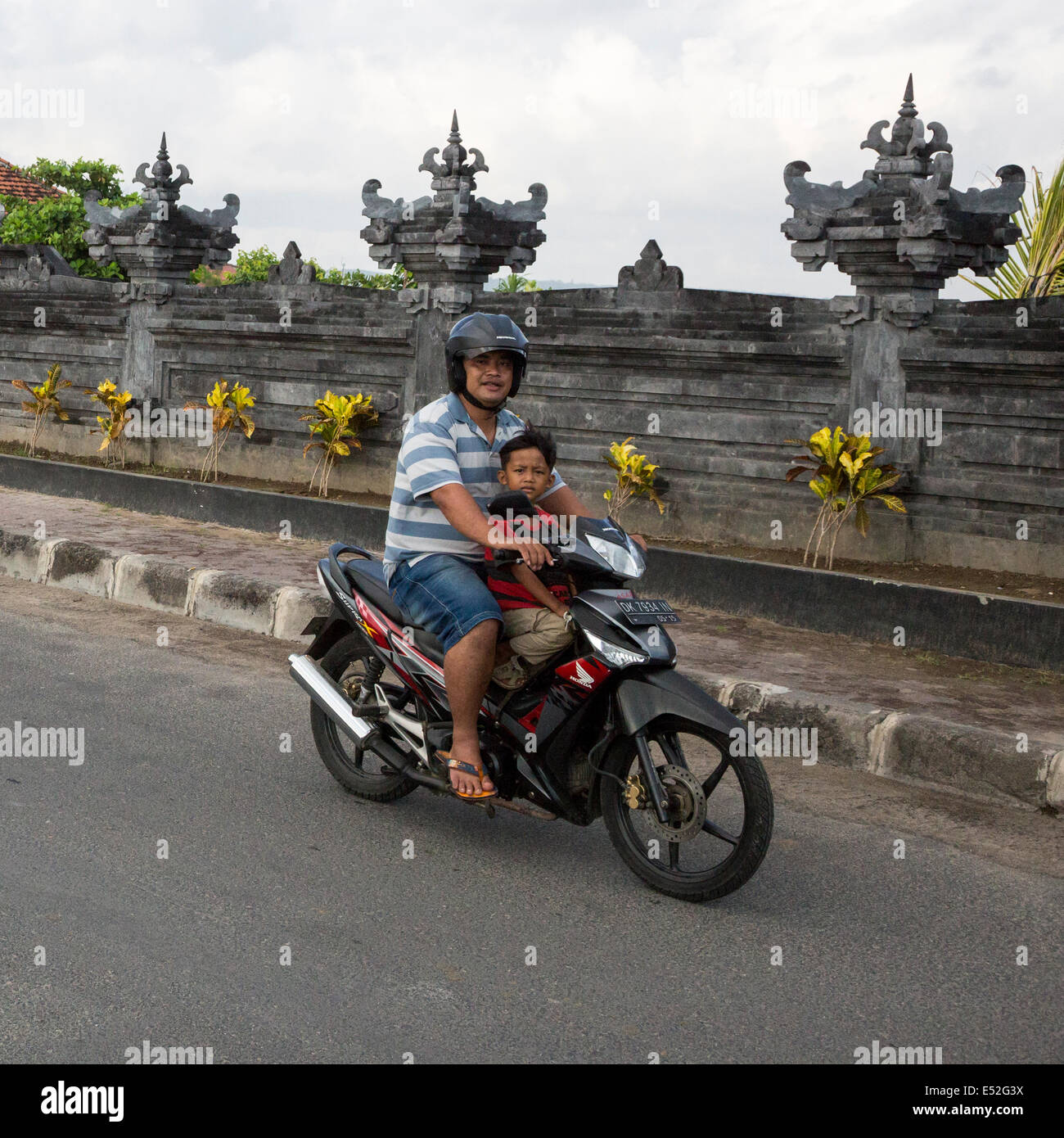 Bali, Indonesia.  Road safety.  Father and Son on Motorbike, no helmet on Boy. Stock Photo